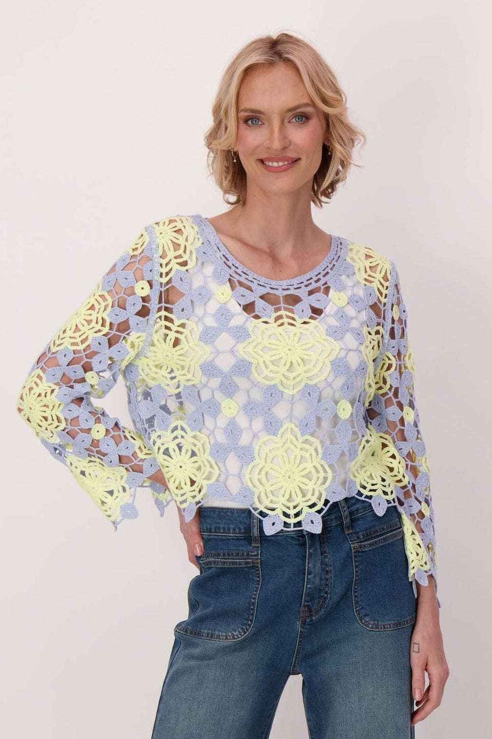 Woman wearing a floral blouse and blue jeans on a white background