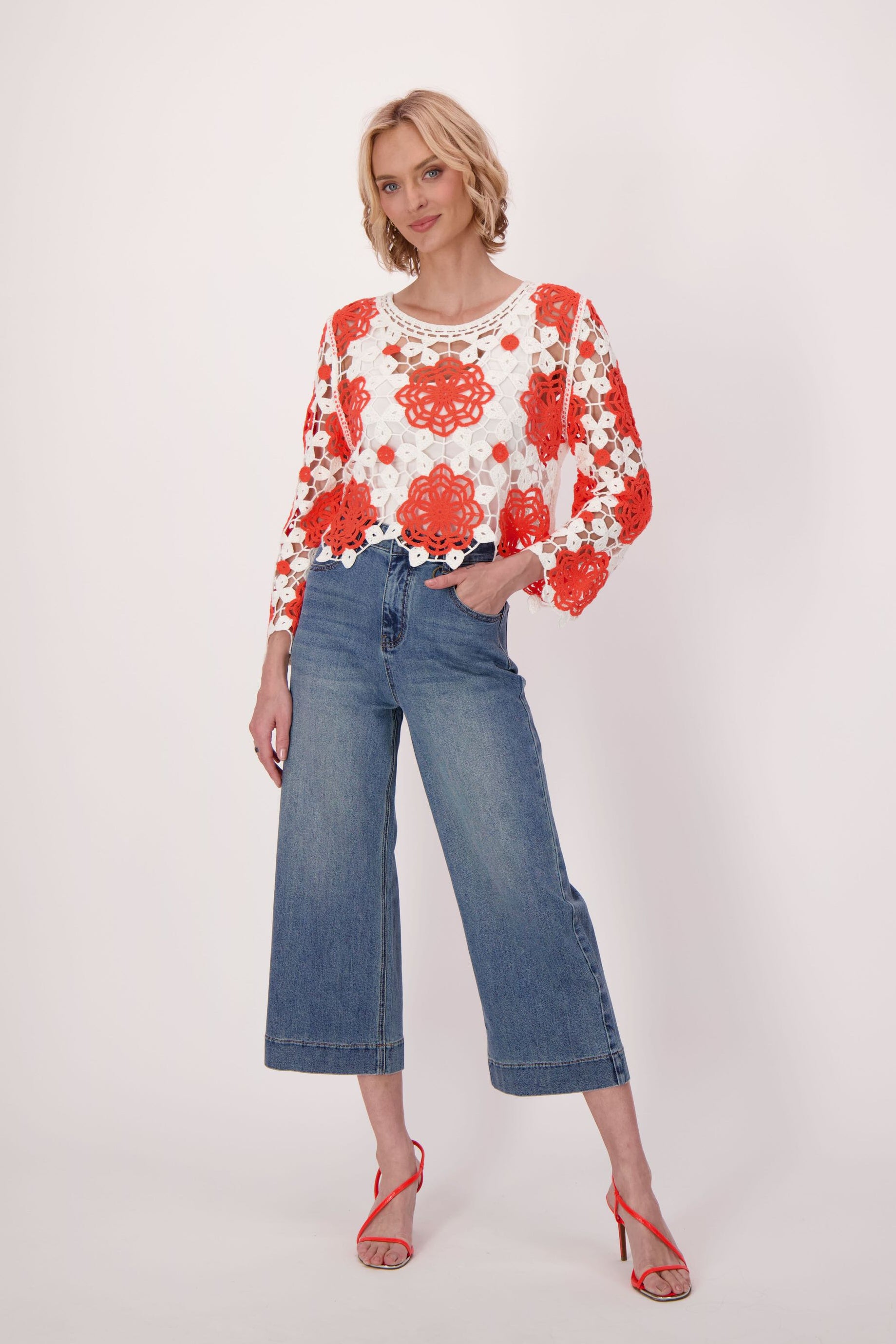 Woman wearing a red and white floral blouse with blue jeans on a white background