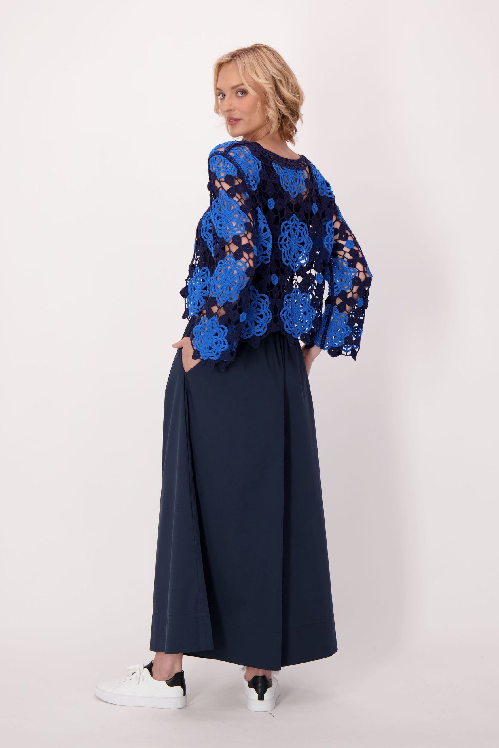 Woman wearing a blue floral top and navy pant on a white background