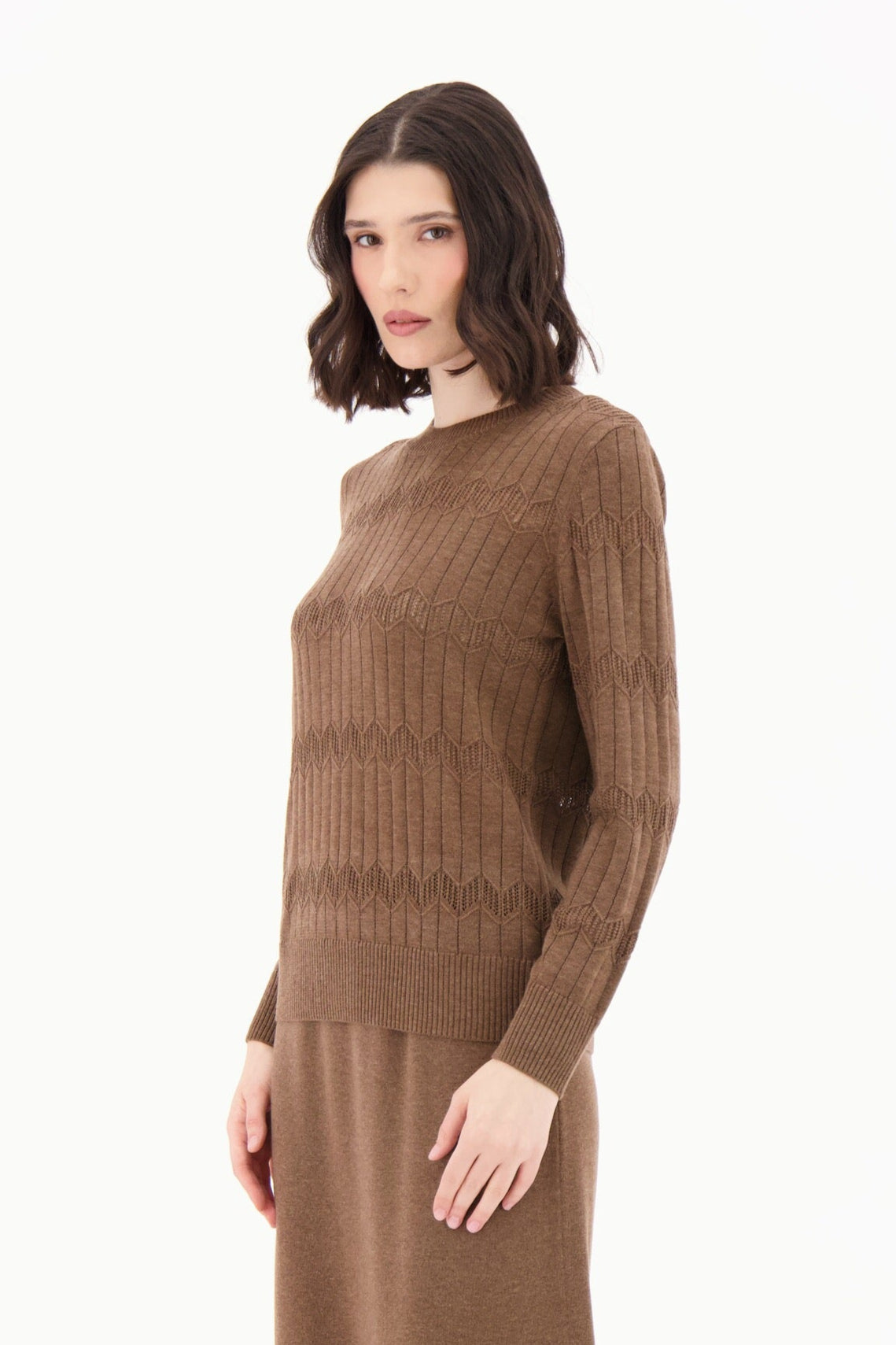 Woman wearing a brown ribbed sweater and skirt set with knee-high brown boots on a white background