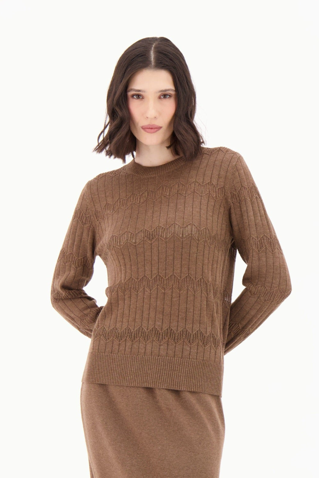 Woman wearing a brown sweater and skirt set with brown boots on a white background