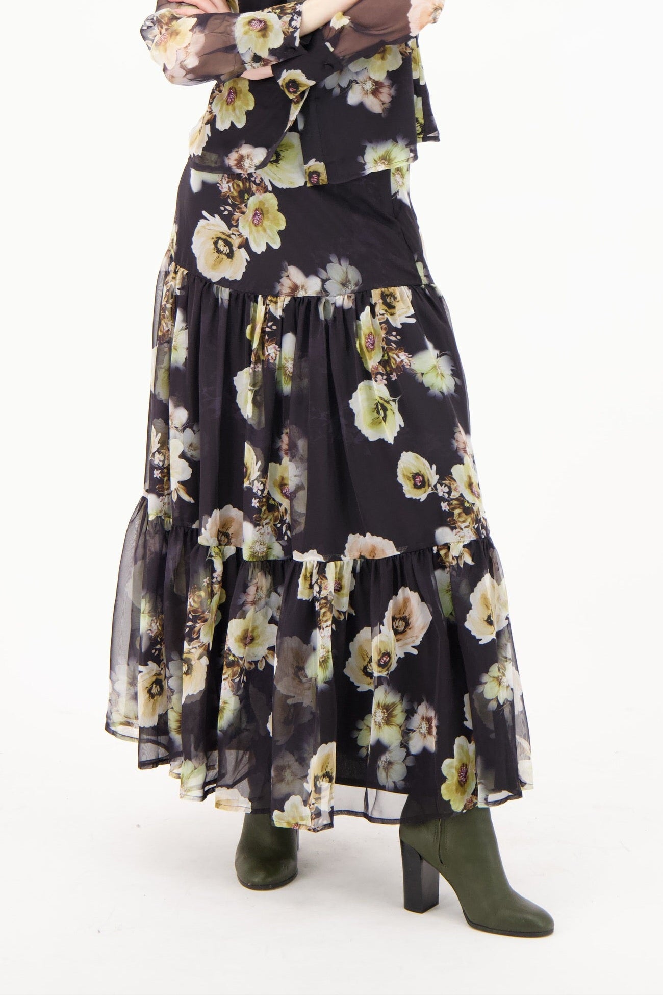 Person wearing a black floral dress with green boots on a white background
