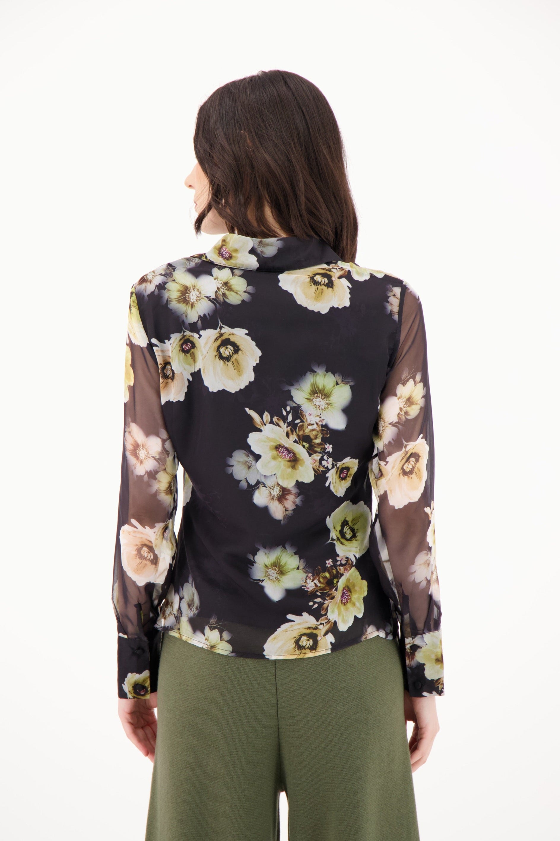 Woman wearing a floral blouse with sheer sleeves on a white background