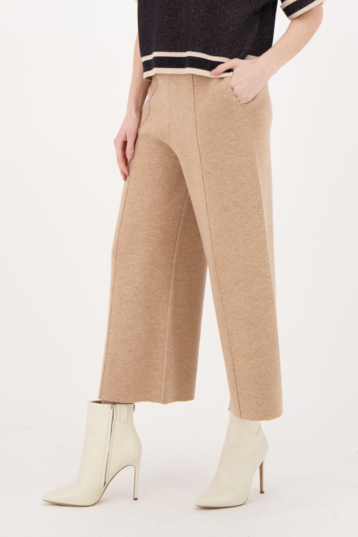 Woman wearing a black sweater and beige pants on a white background