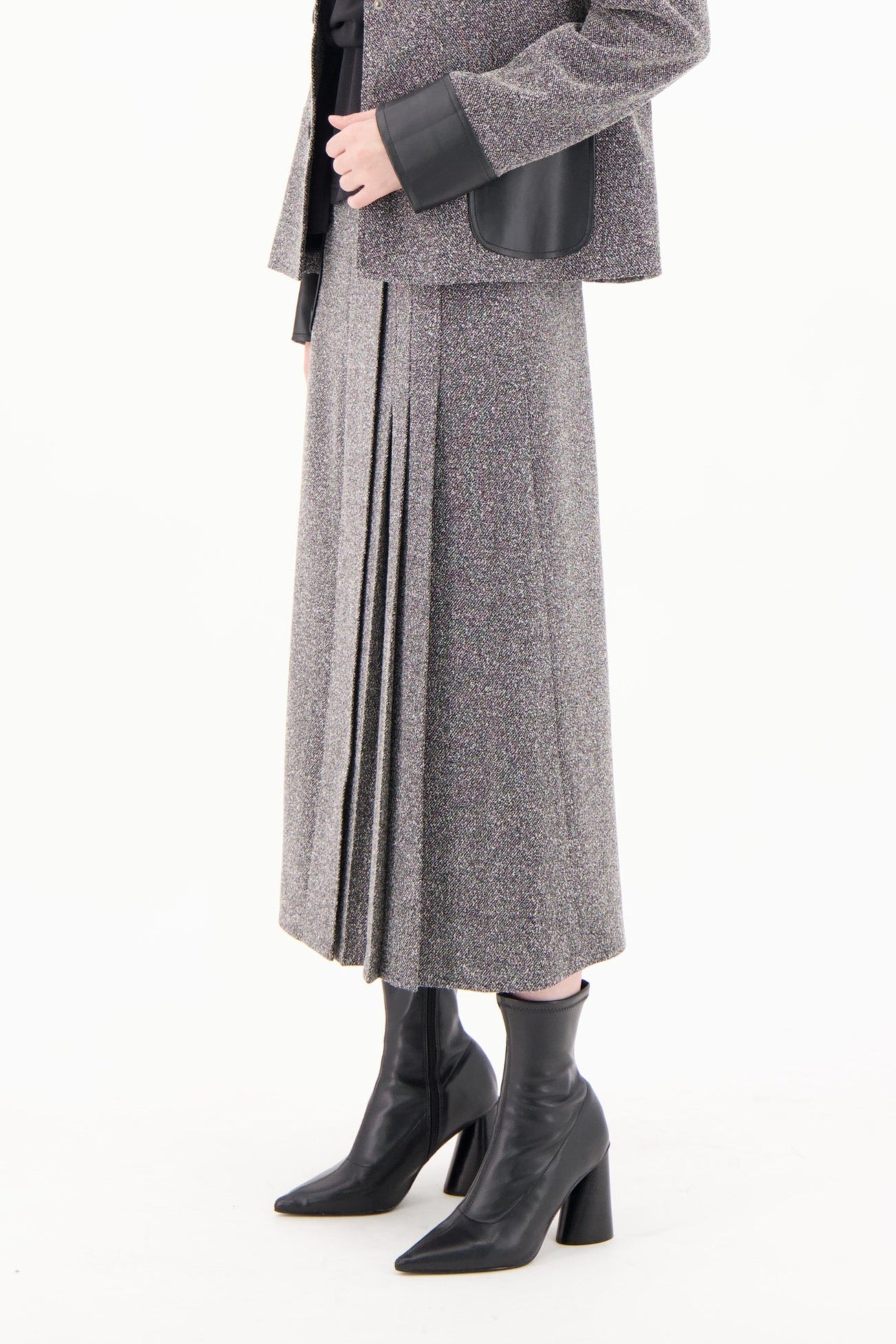 Woman wearing a gray coat and skirt set on a white background