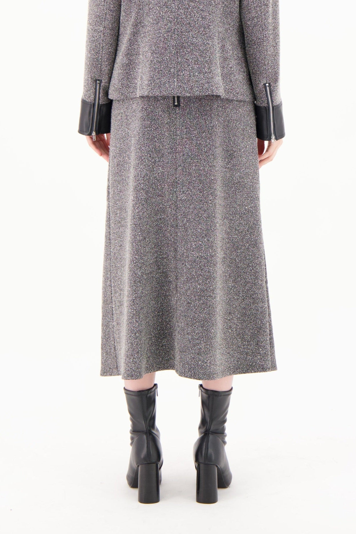Woman wearing a gray coat with black leather accents on a white background