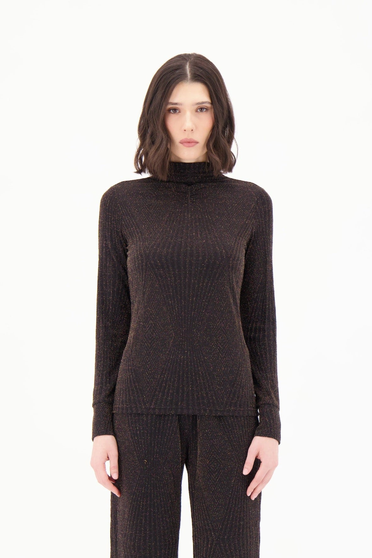 Woman wearing a brown ribbed turtleneck sweater and pants on a white background
