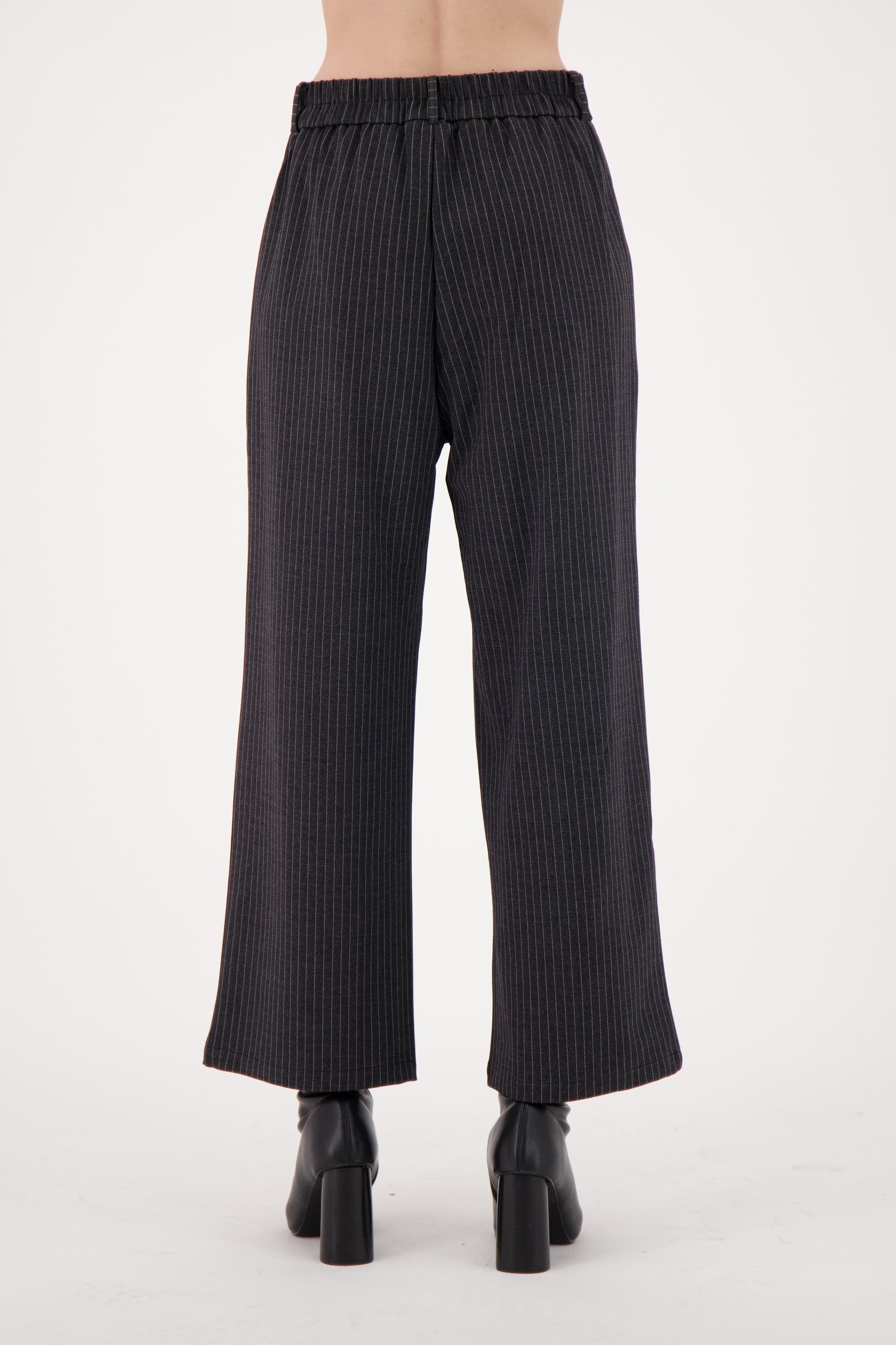 Black pinstripe pants worn by a person on a white background