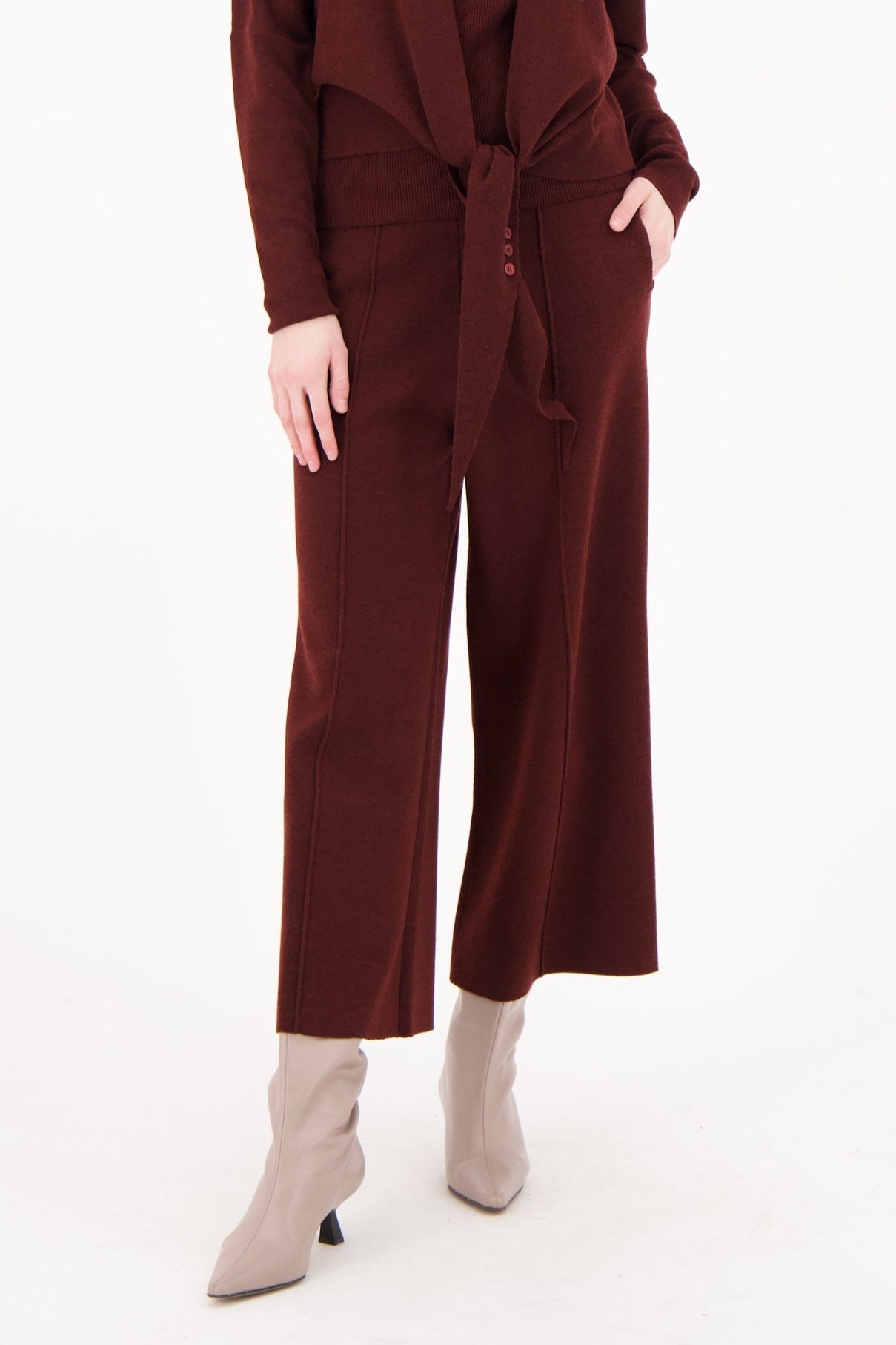 Woman wearing a maroon jumpsuit on a white background