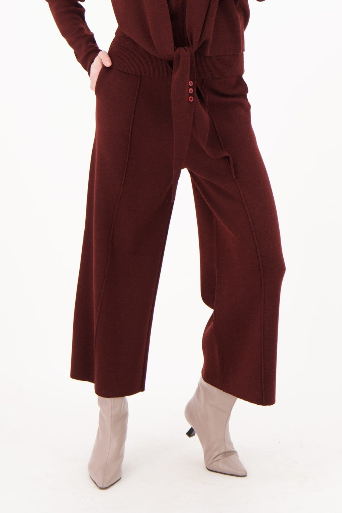 Woman wearing a maroon jumpsuit on a white background