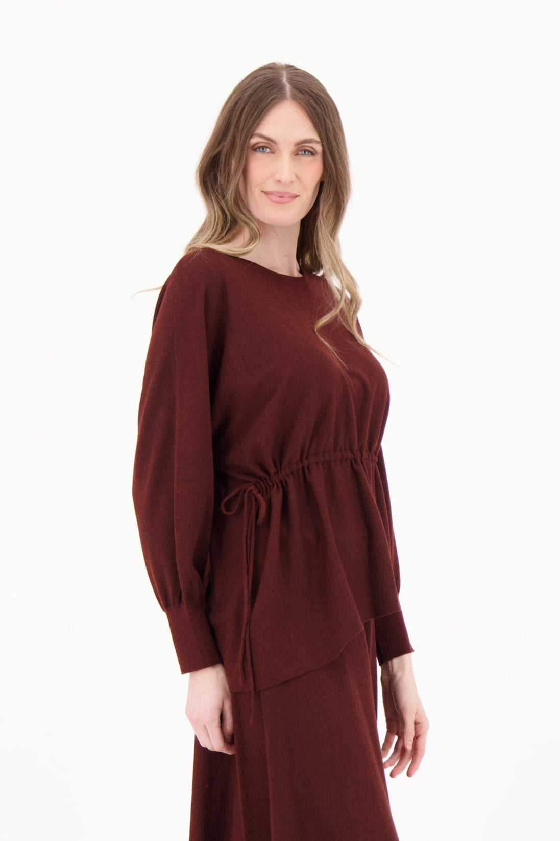 Woman wearing a brown dress with long sleeves and a belt on a white background