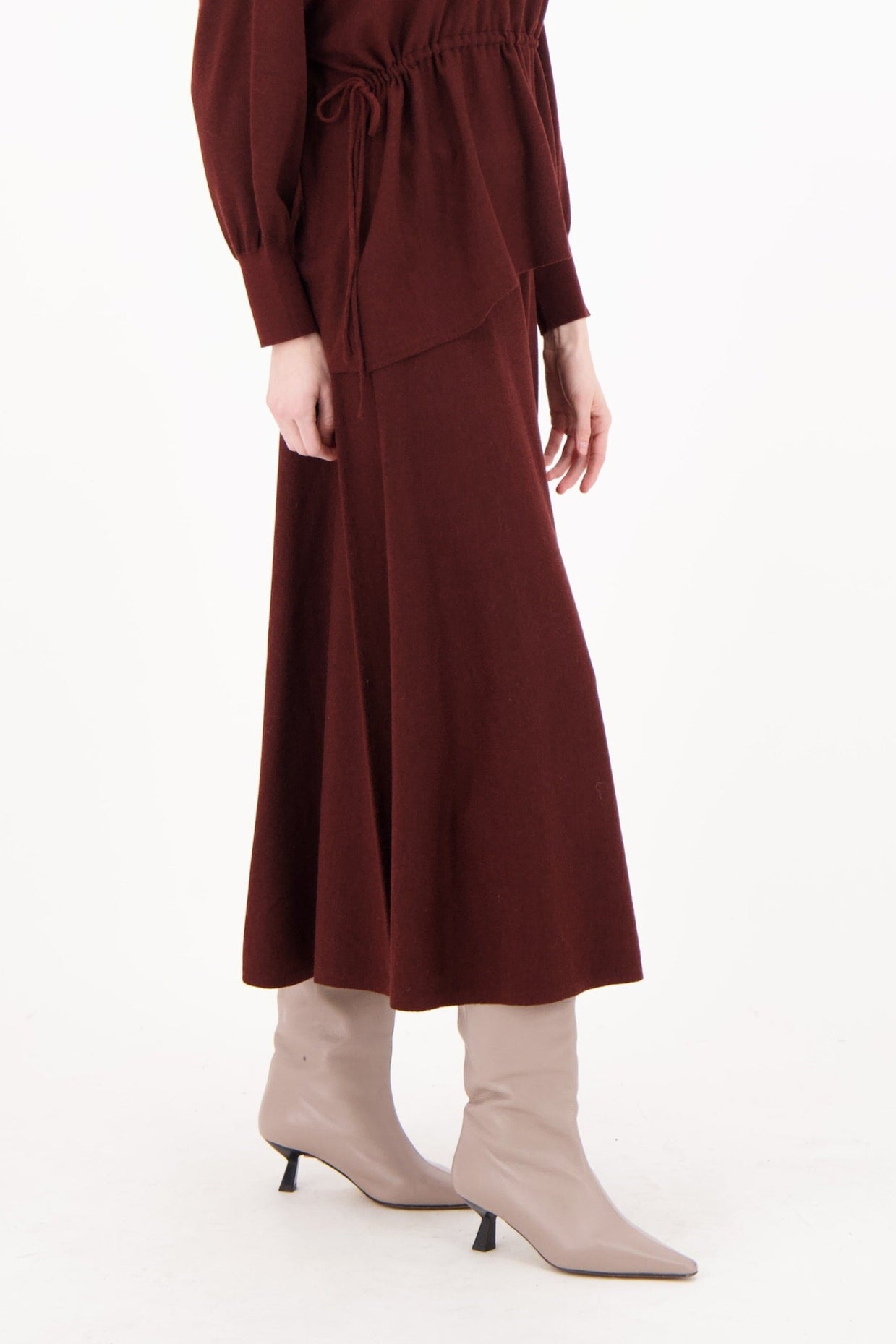 Woman wearing a brown dress with long sleeves and a belt on a white background