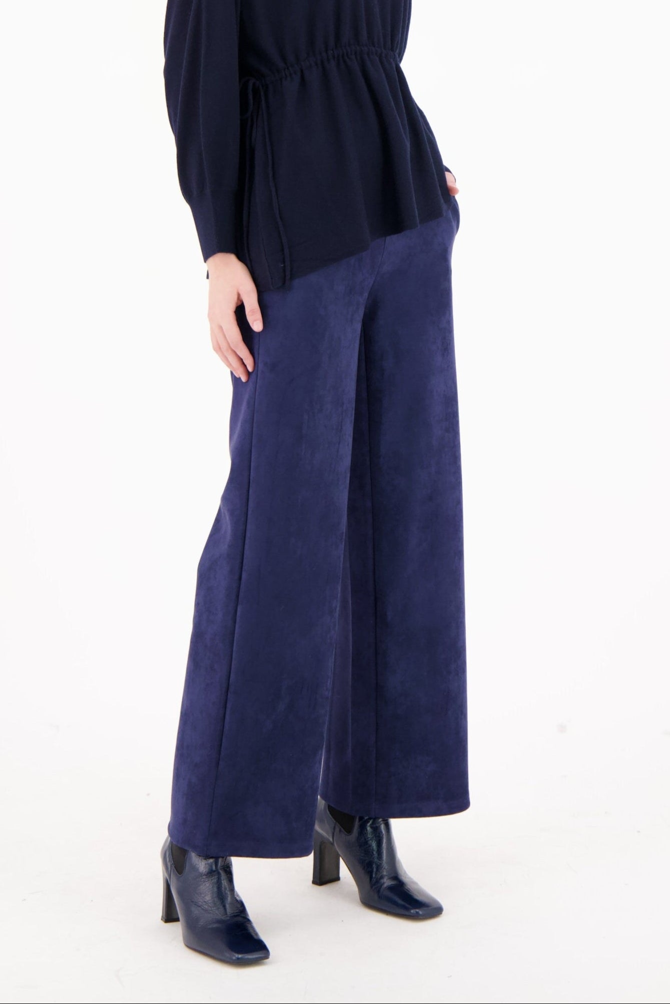 Woman wearing a navy blue outfit with wide-leg pants on a white background