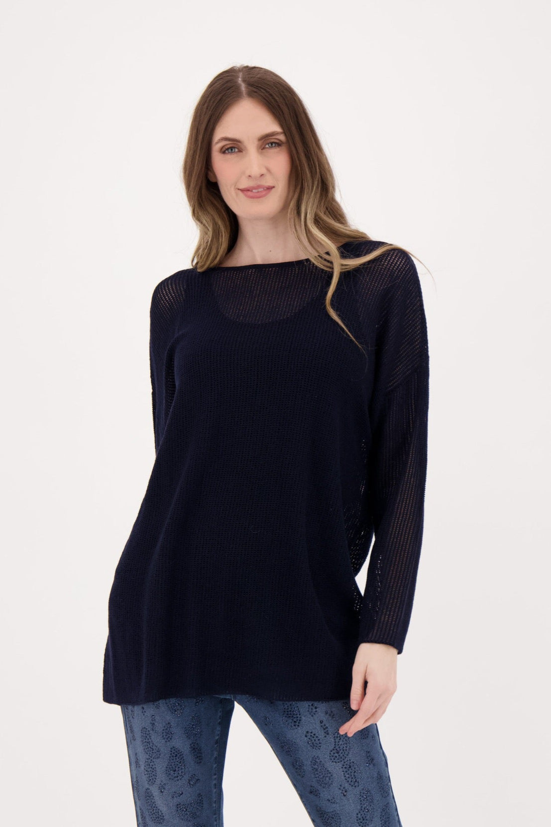 Woman wearing a black sweater and blue jeans on a white background