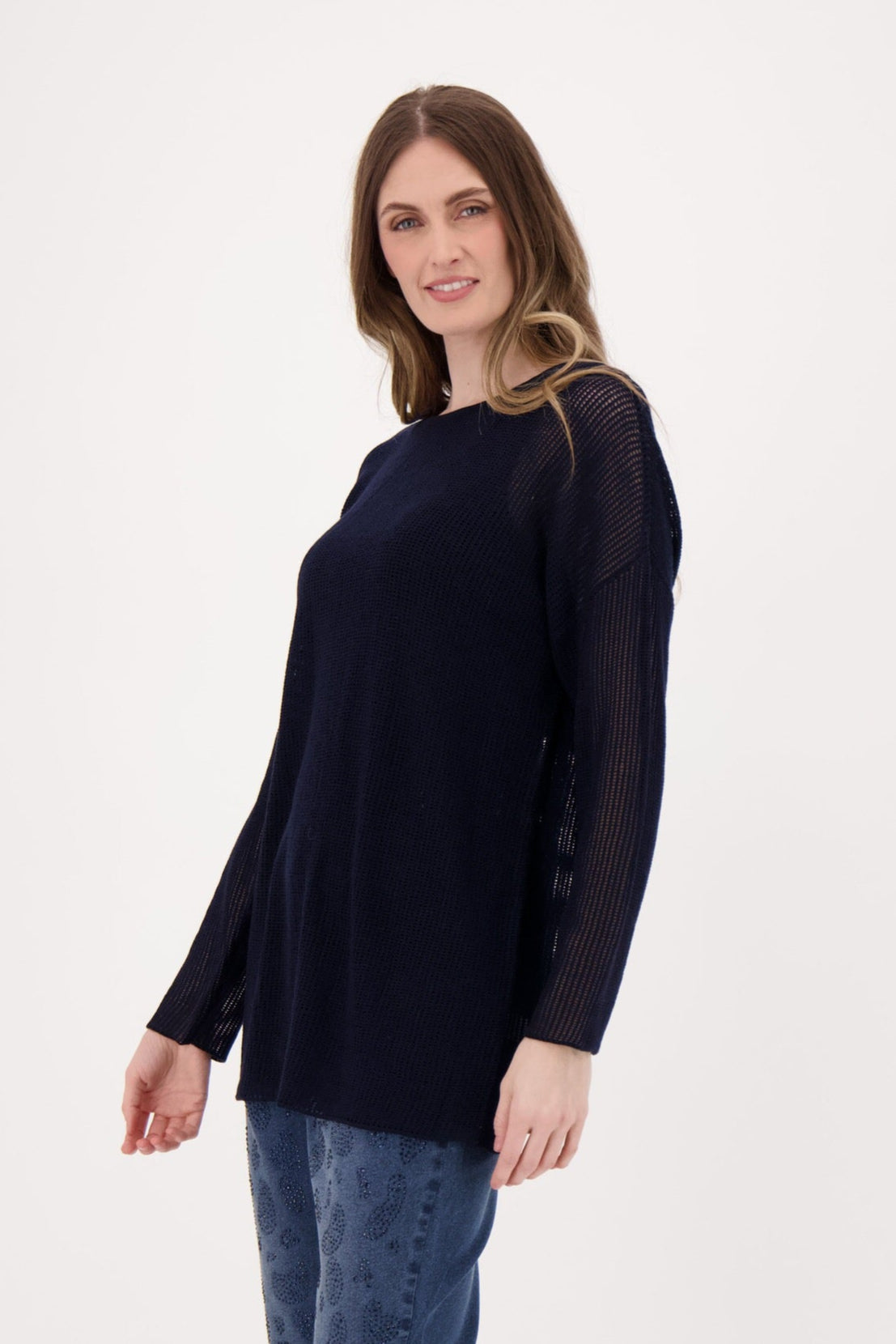 Woman wearing a black sweater and blue jeans on a white background