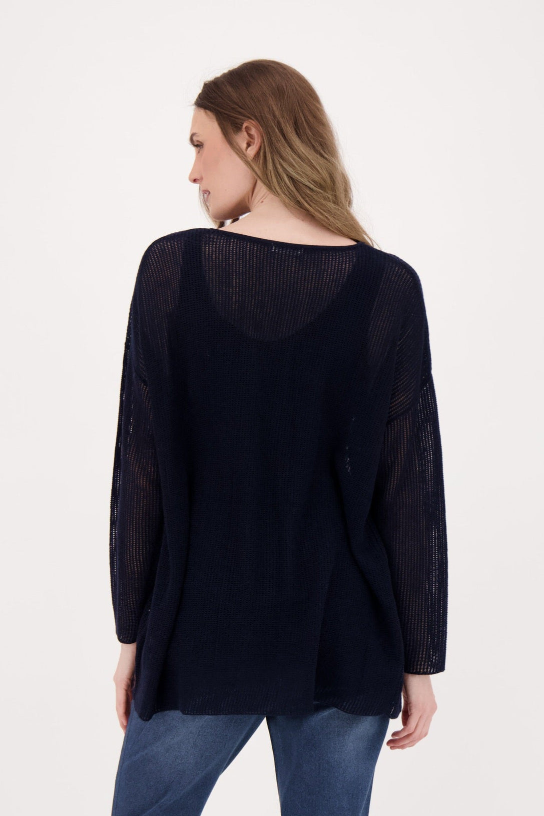 Woman wearing a black long-sleeve top and blue jeans on a white background