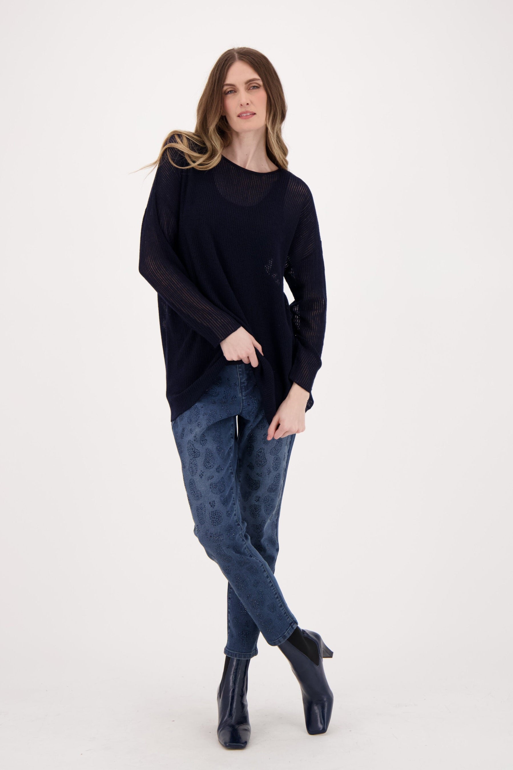 Woman wearing a black sweater and blue jeans on a white background