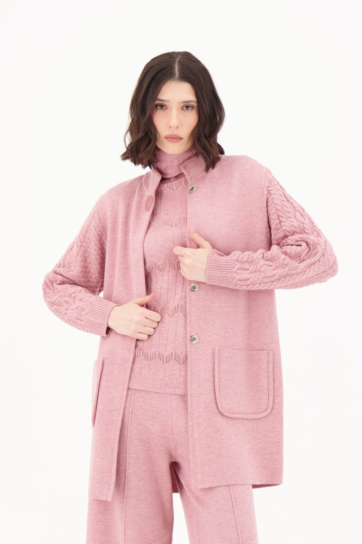 Person wearing a pink outfit with a coat and pants on a white background