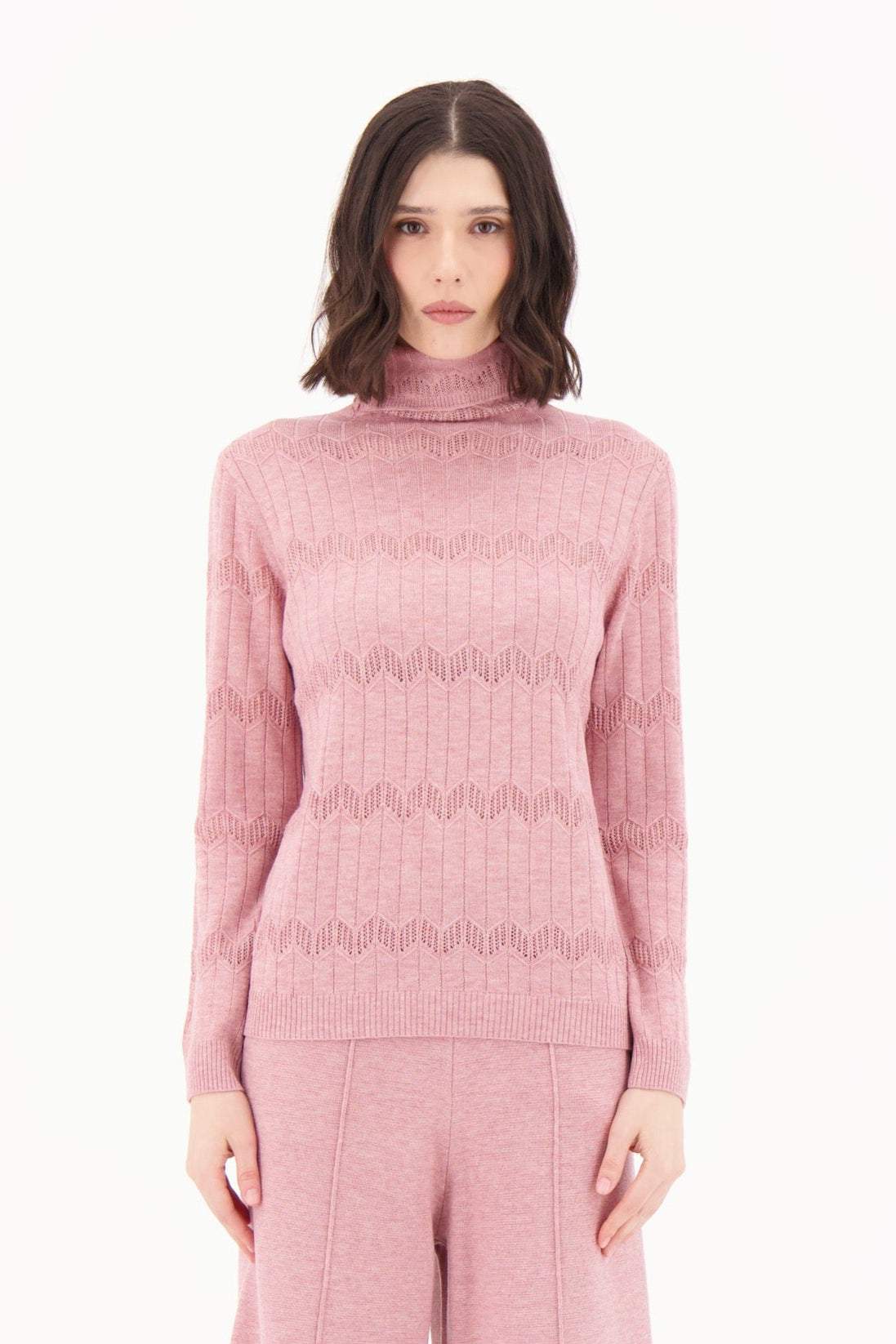 Woman wearing a pink knit outfit on a white background
