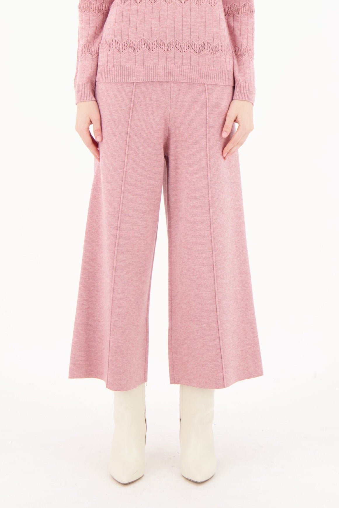 Woman wearing a pink knit outfit on a white background