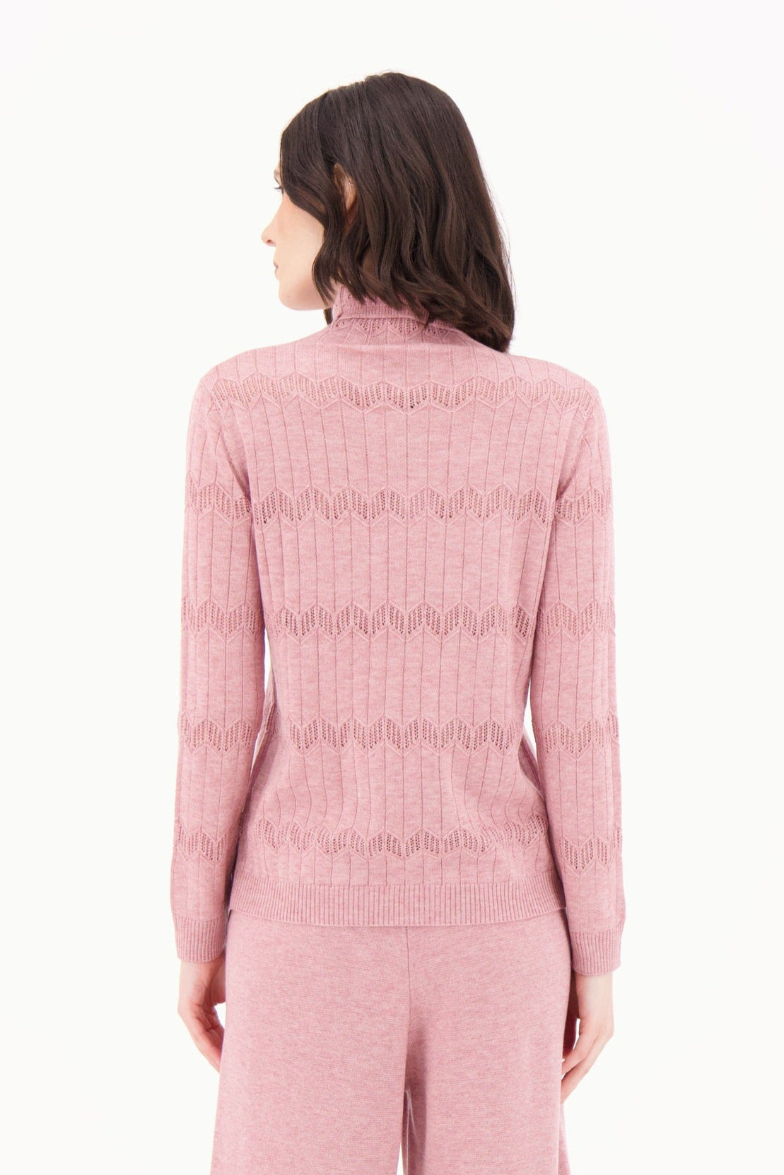 Person wearing a pink ribbed knit outfit on a white background
