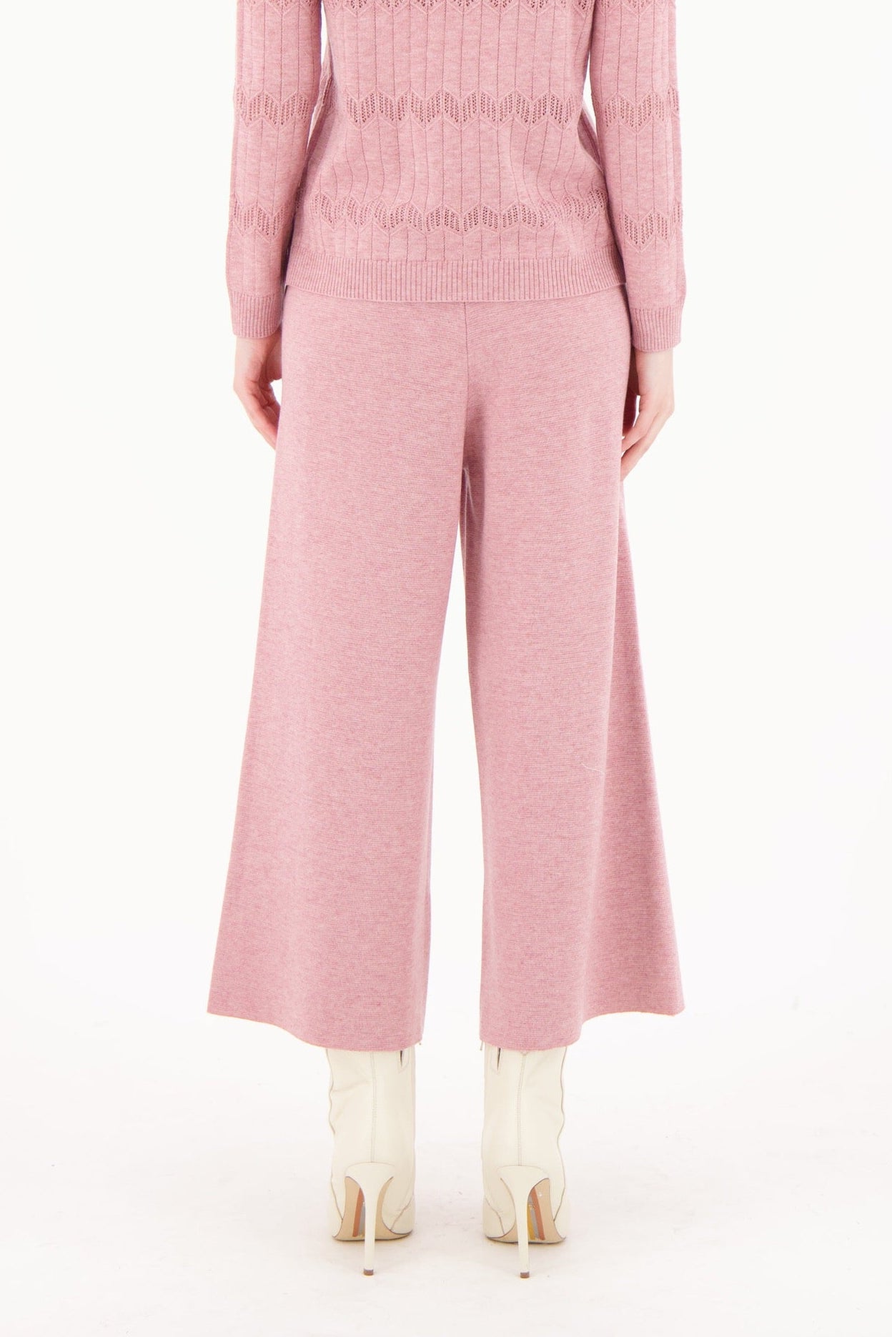 Person wearing a pink ribbed knit outfit on a white background