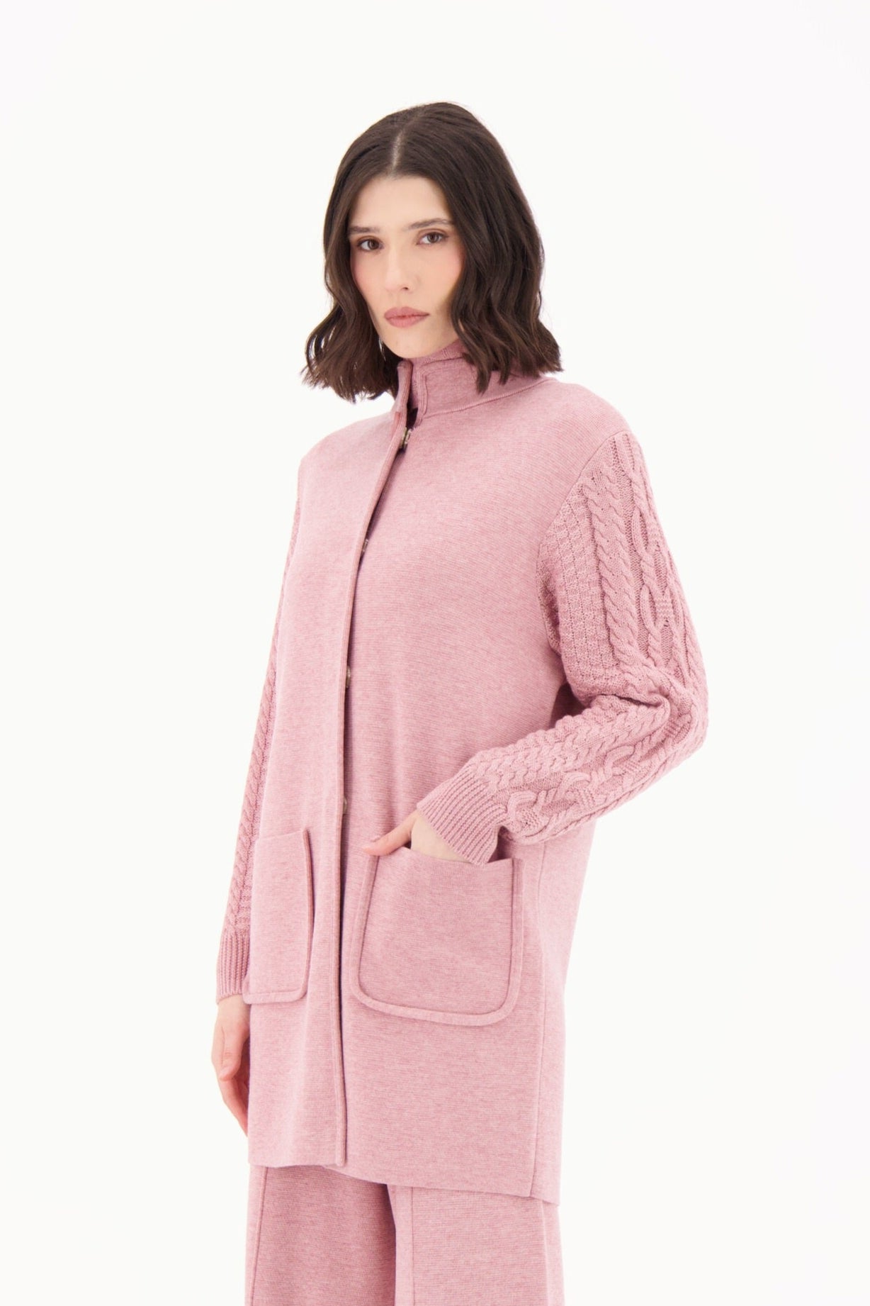 Woman wearing a pink outfit with a matching coat and pants on a white background