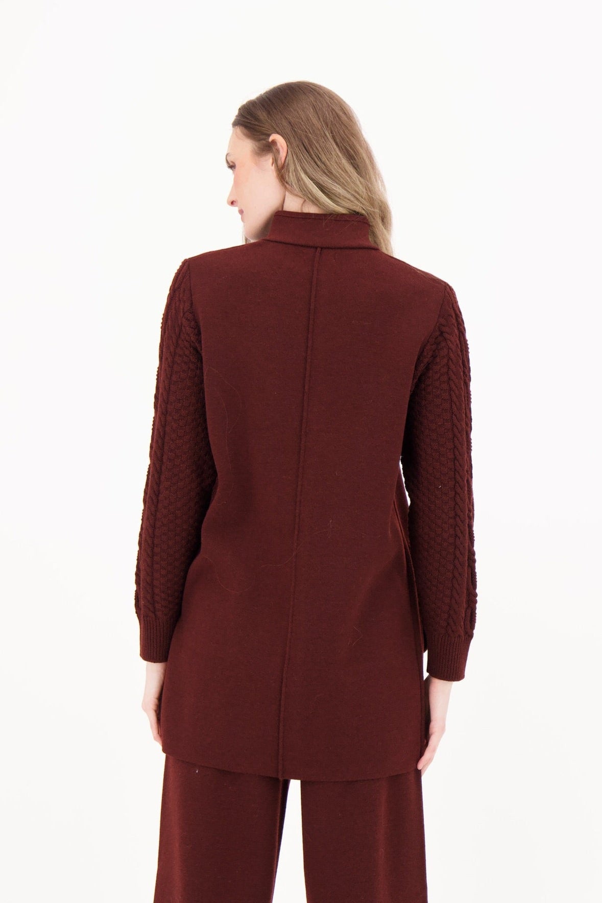 Woman wearing a burgundy coat and pants on a white background