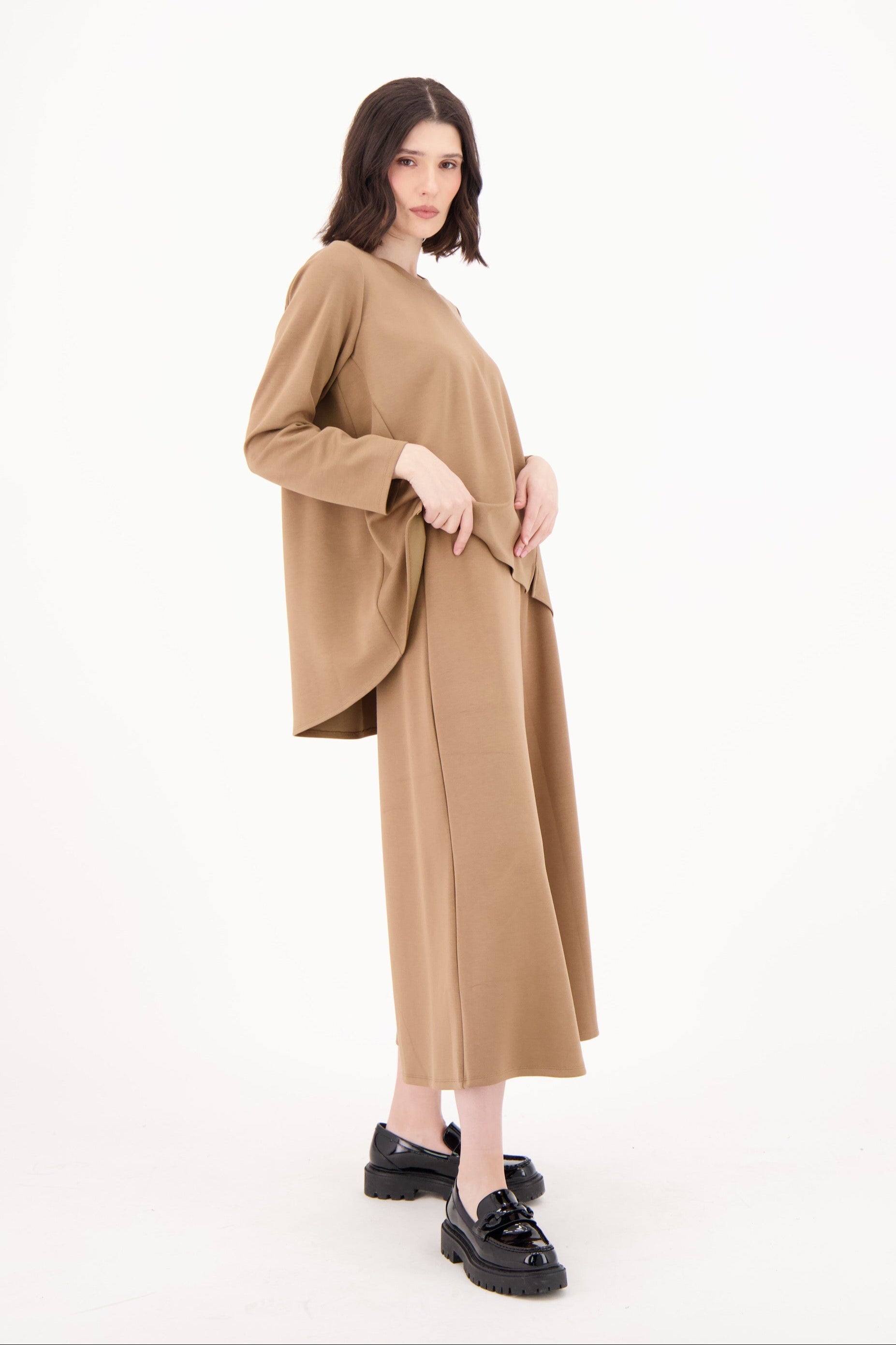 Woman wearing a long beige dress on a white background
