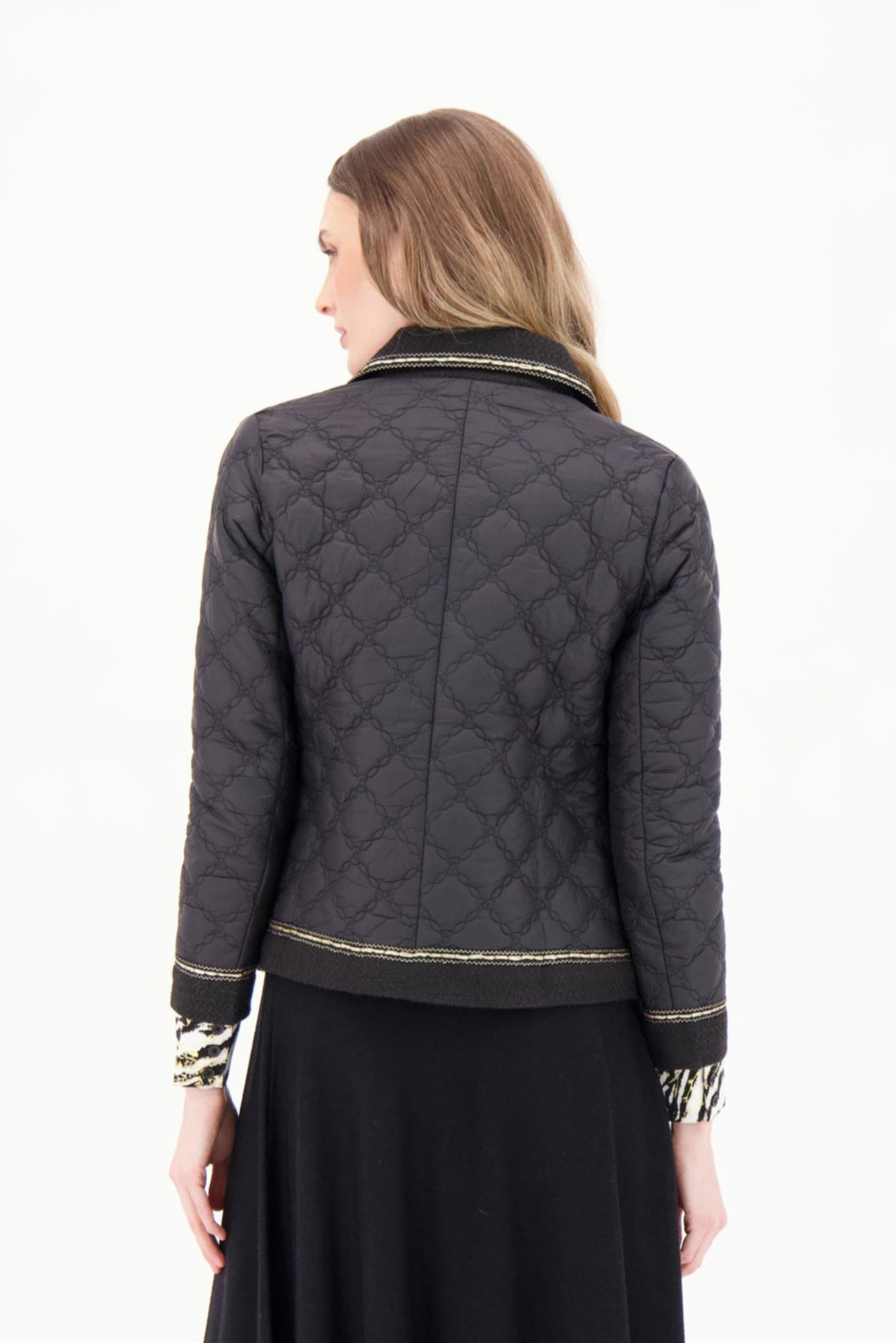 Woman wearing a quilted jacket and black skirt on a white background