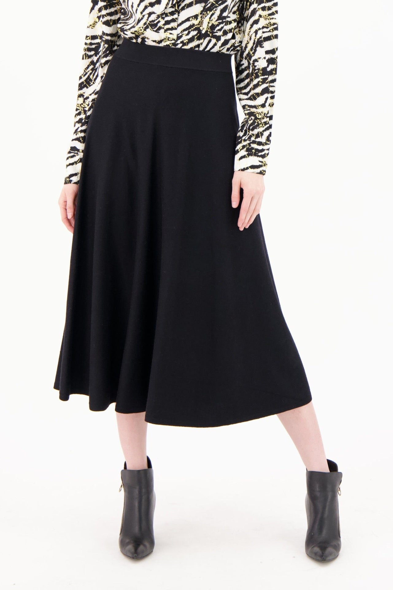 Woman wearing a patterned blouse and black skirt on a white background