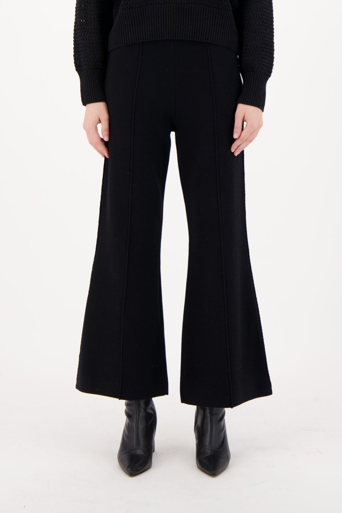 Woman wearing a black outfit with striped collar on a white background