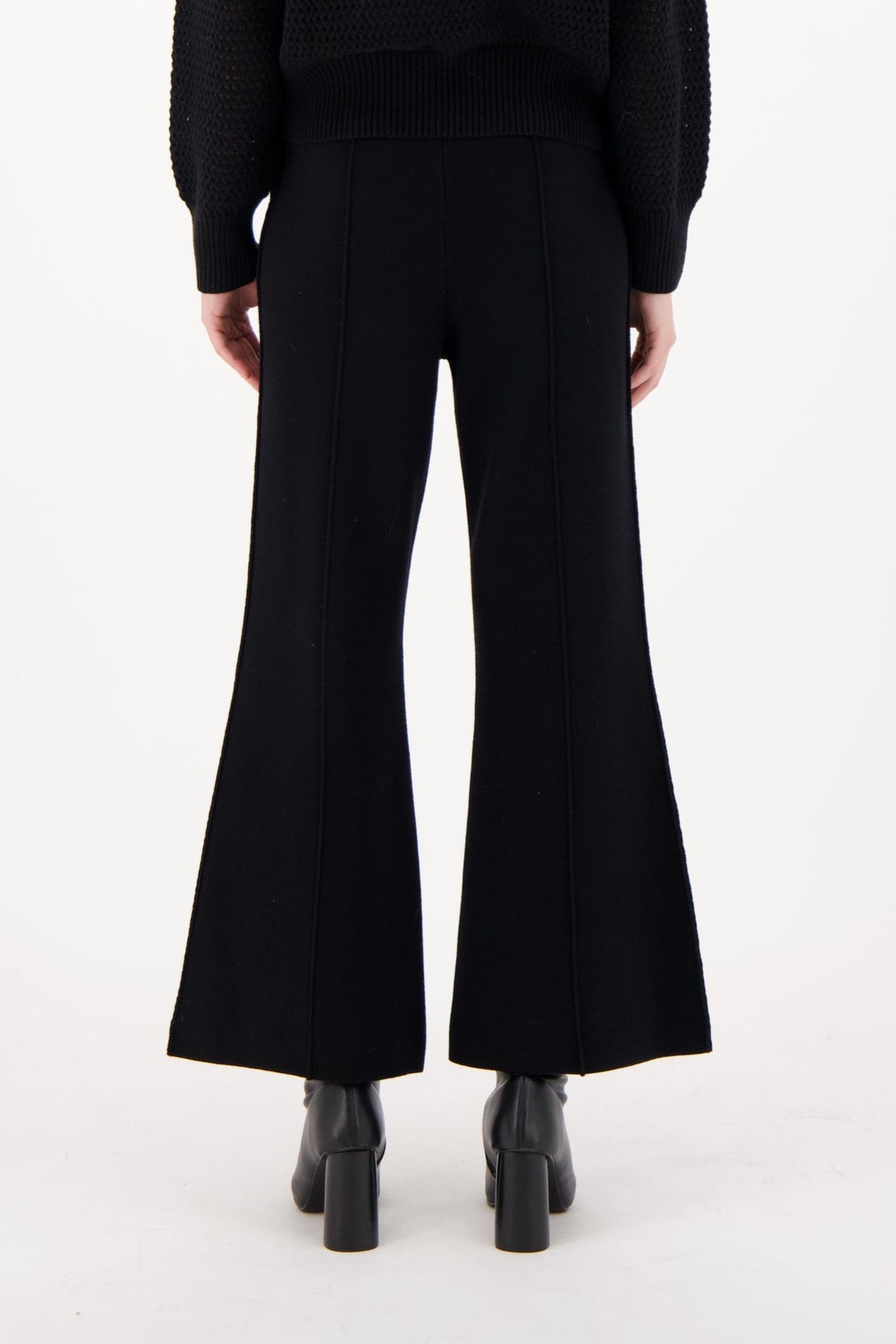 Person wearing a black outfit with embellishments on a white background