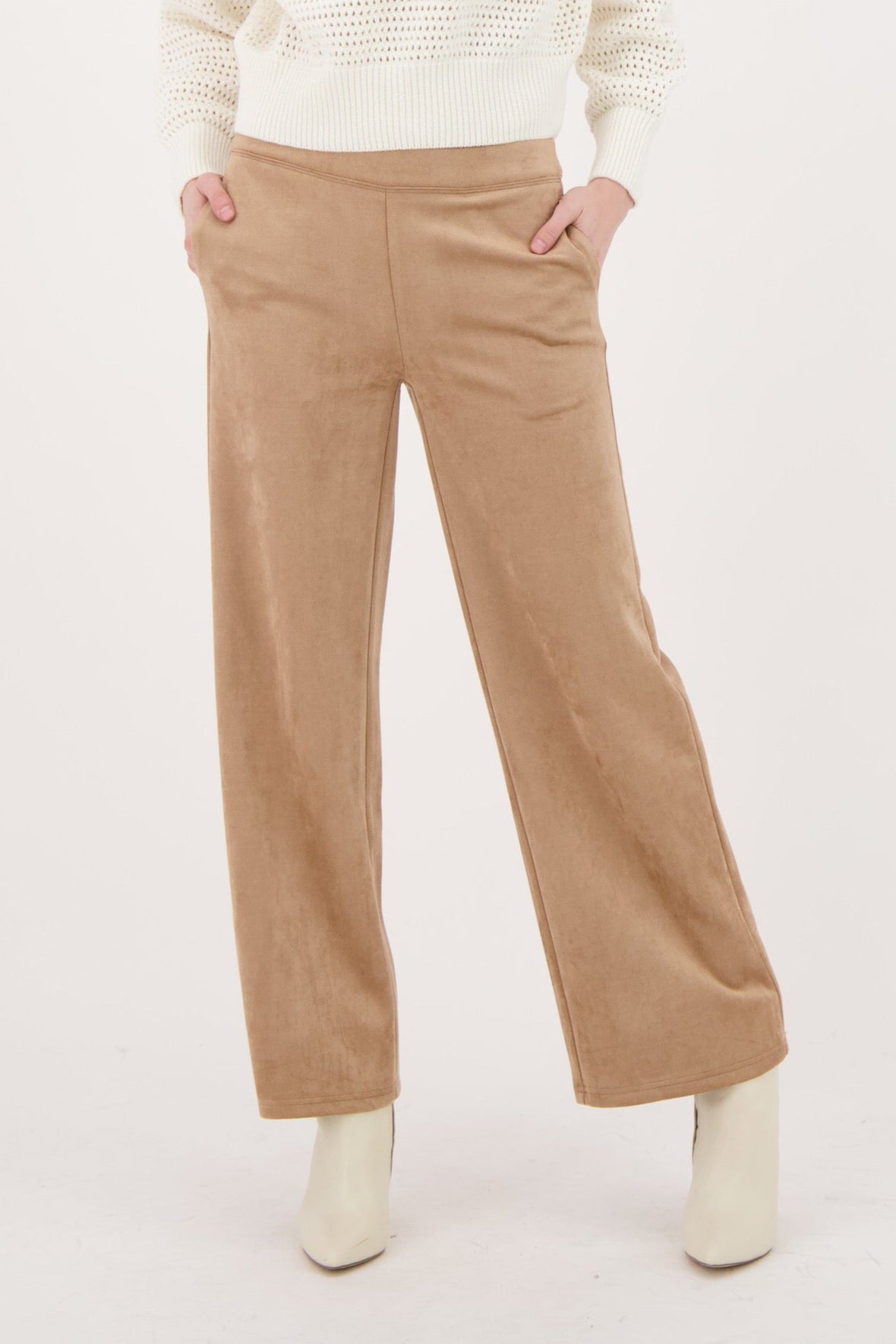 Woman wearing a cream sweater and beige pants on a white background