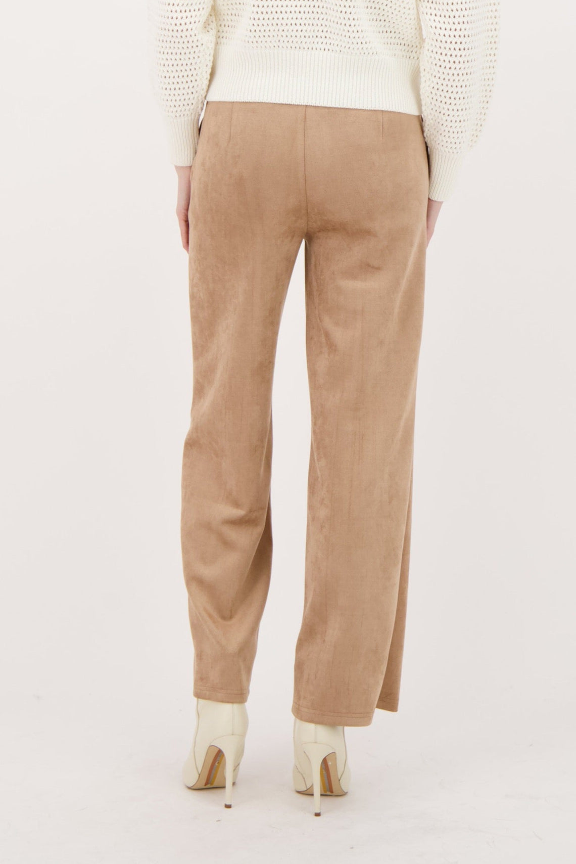 Woman wearing a cream sweater and beige pants on a white background