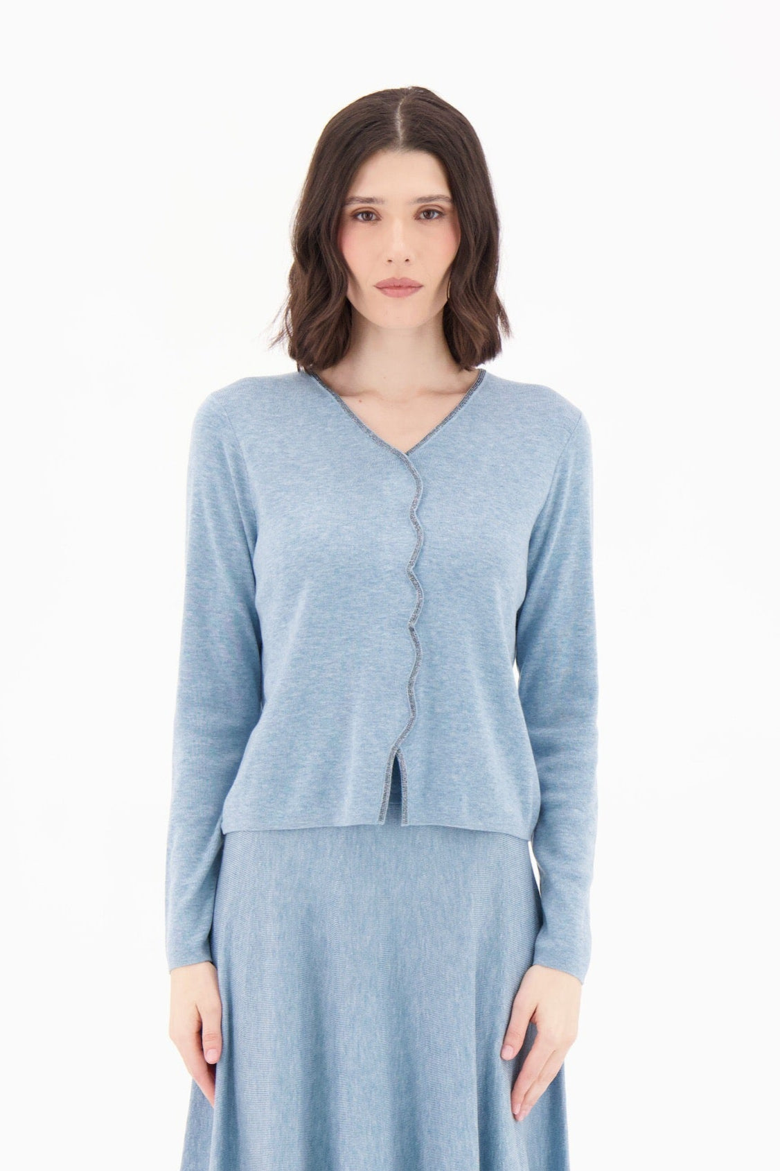 Woman wearing a light blue cardigan and dress on a white background