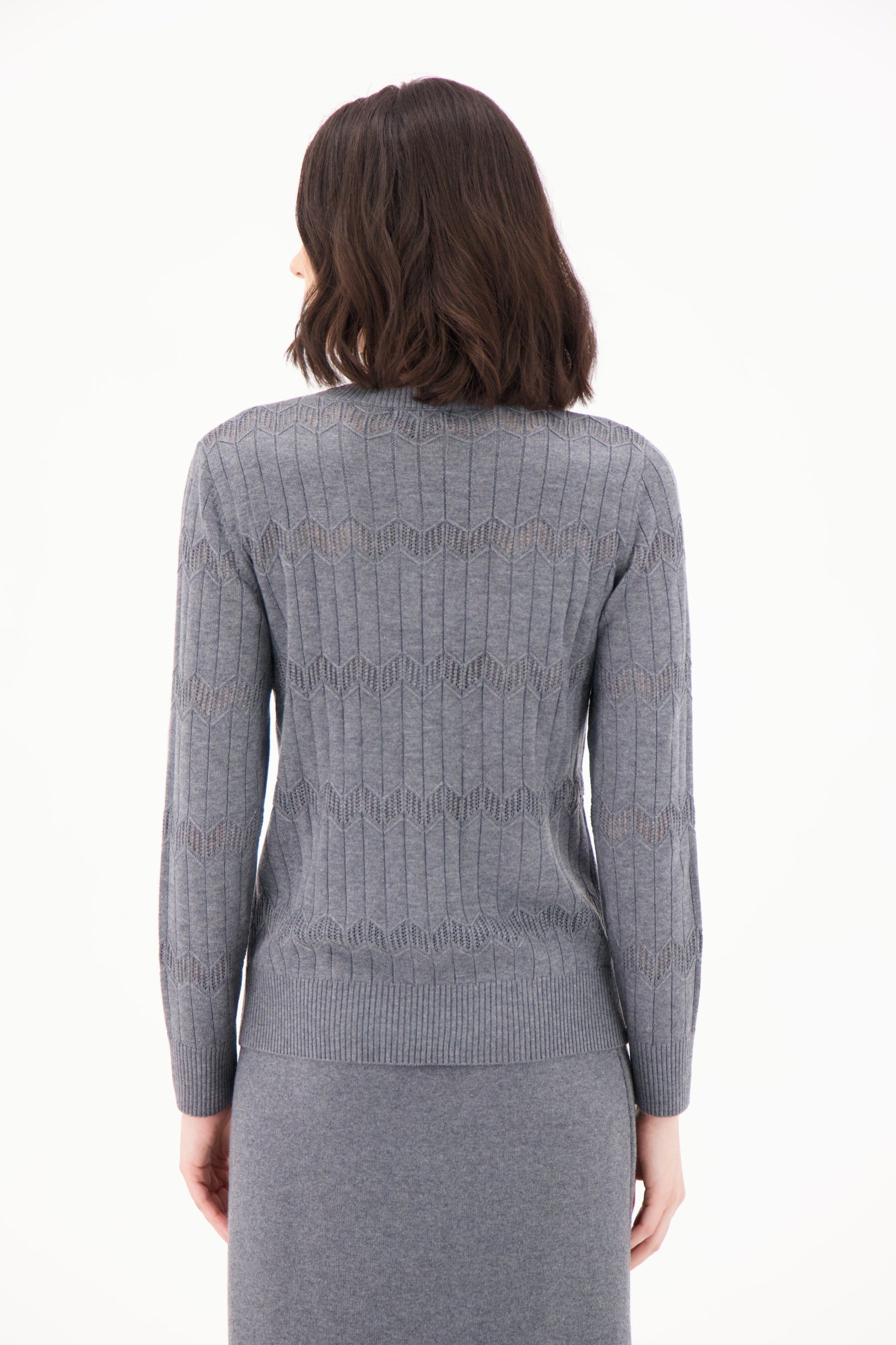 Woman wearing a gray knit dress with a subtle pattern on a white background