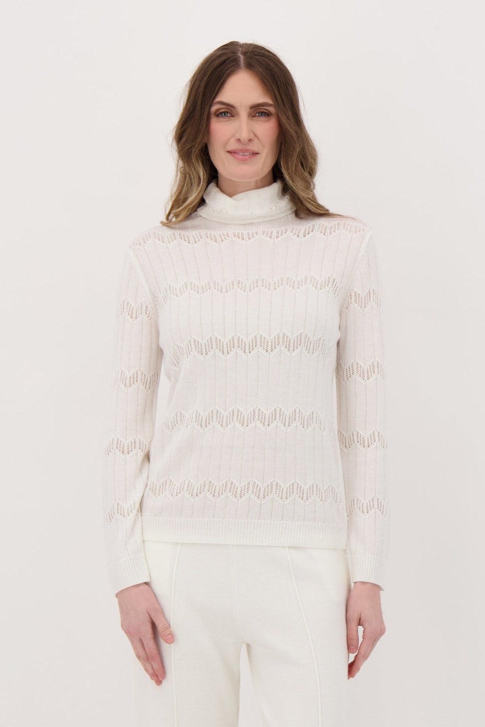 Person wearing a white turtleneck sweater and pants on a white background