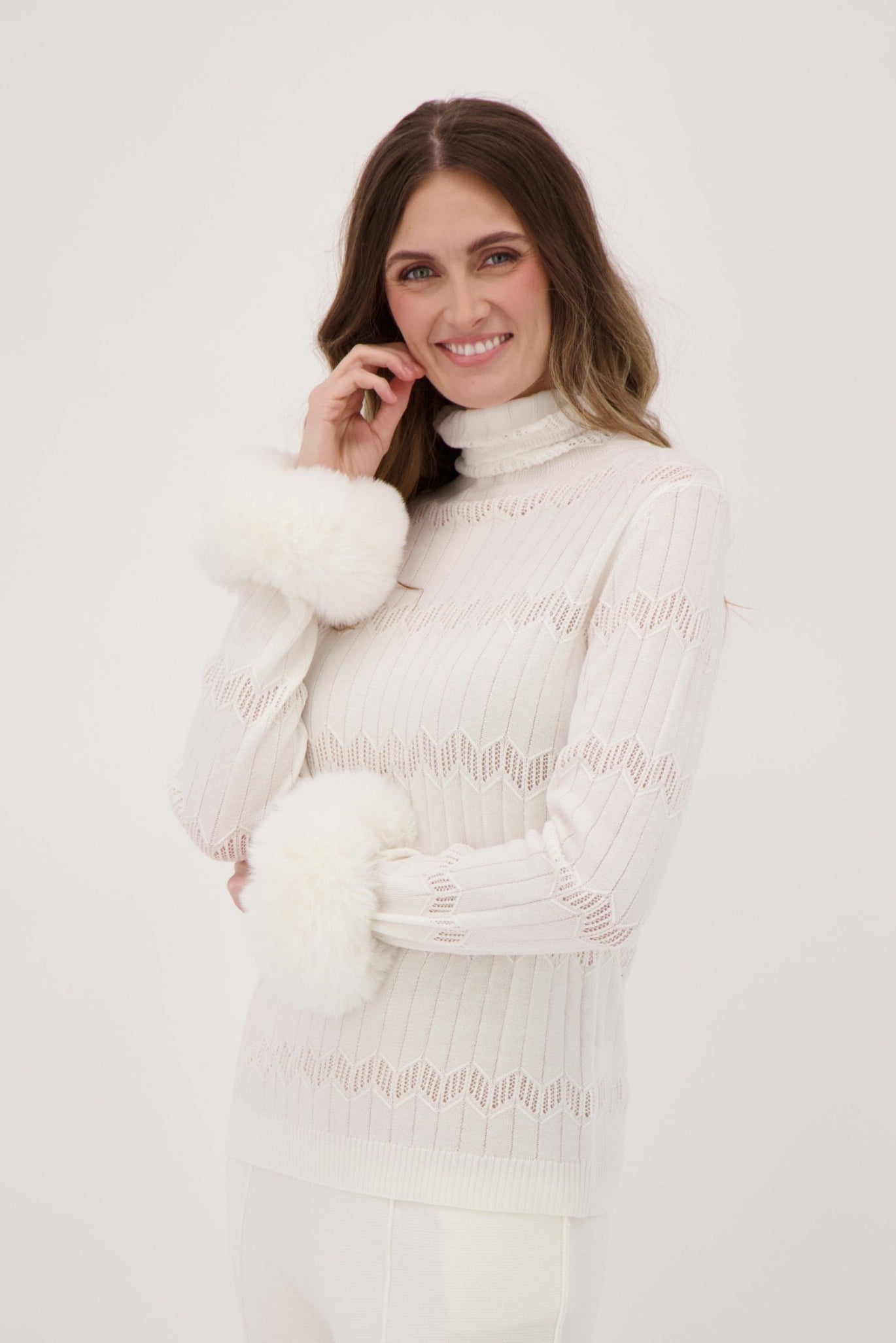 Woman wearing a white outfit with a turtleneck and pants against a white background