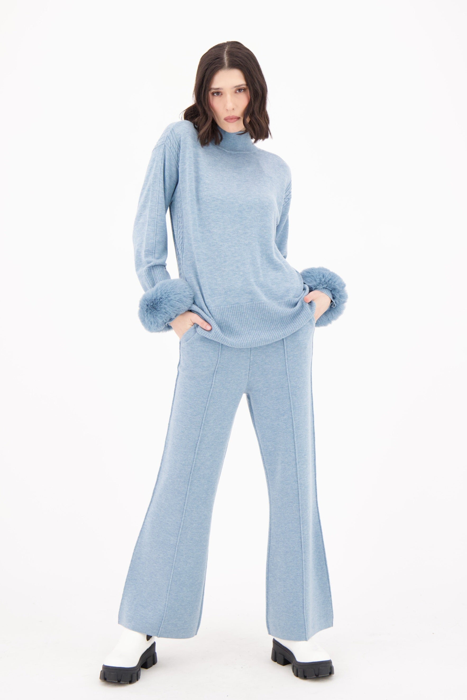 Woman wearing a light blue outfit with matching gloves and pants on a white background