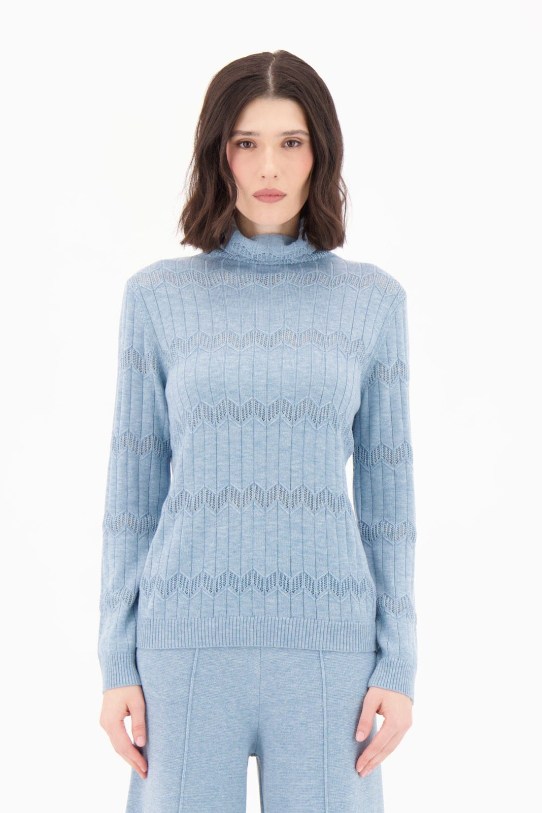 Woman wearing a light blue knit outfit on a white background