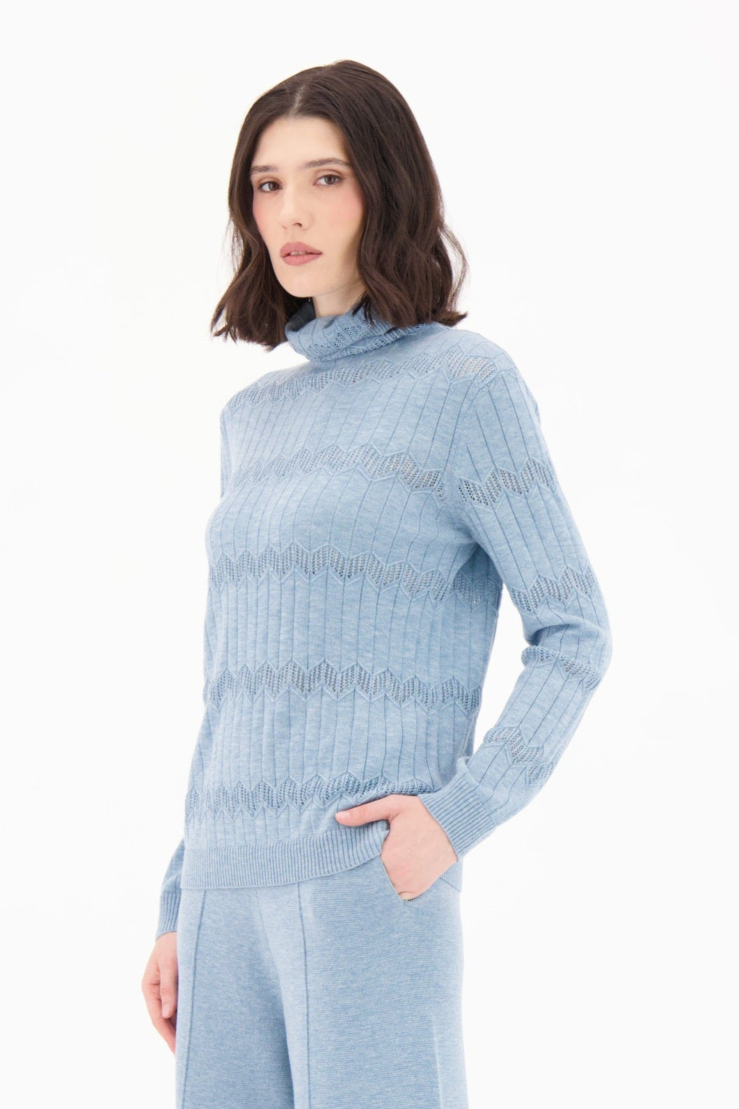 Woman wearing a light blue ribbed sweater and matching pants on a white background