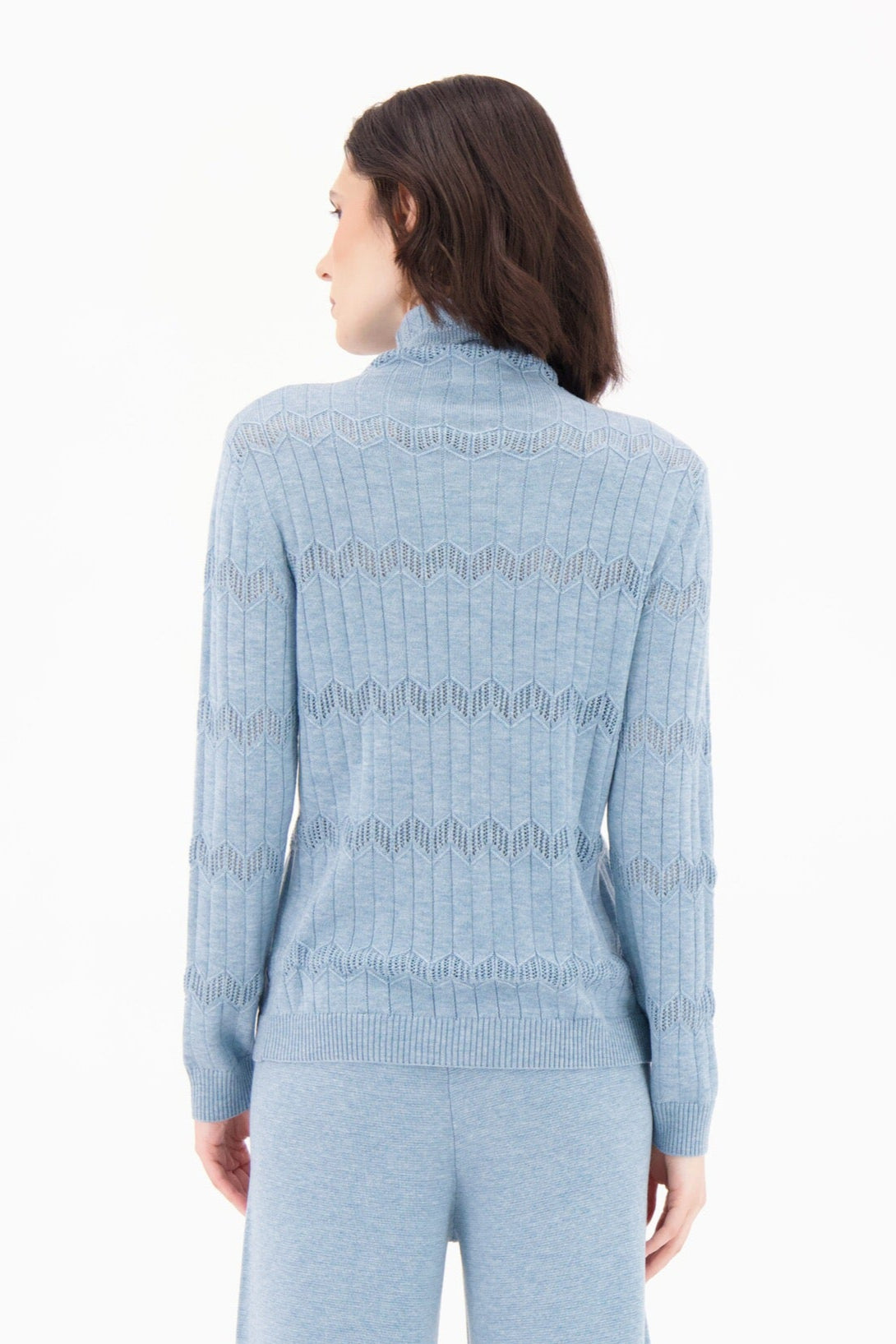 Woman wearing a light blue ribbed knit outfit on a white background