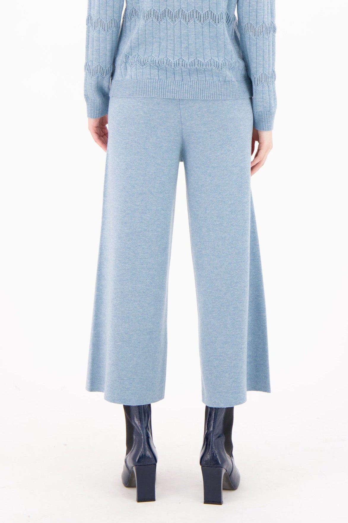 Woman wearing a light blue ribbed knit outfit on a white background