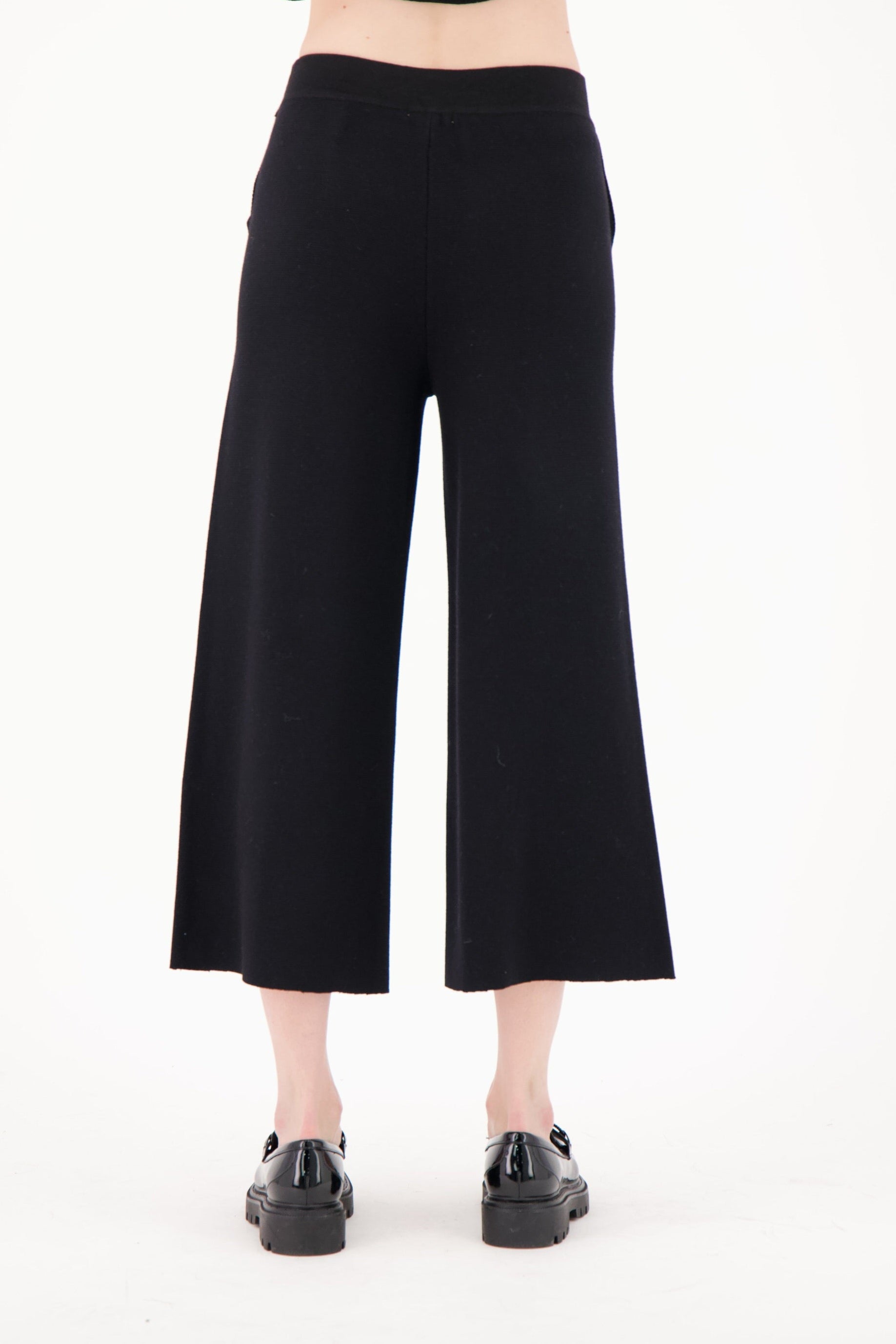 Person wearing black wide-leg pants on a white background