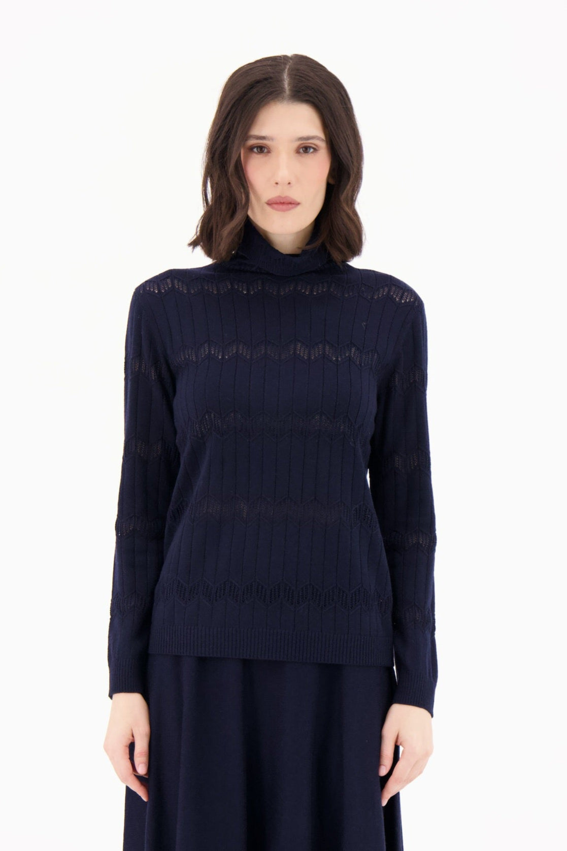 Woman wearing a navy blue turtleneck sweater and skirt set on a white background