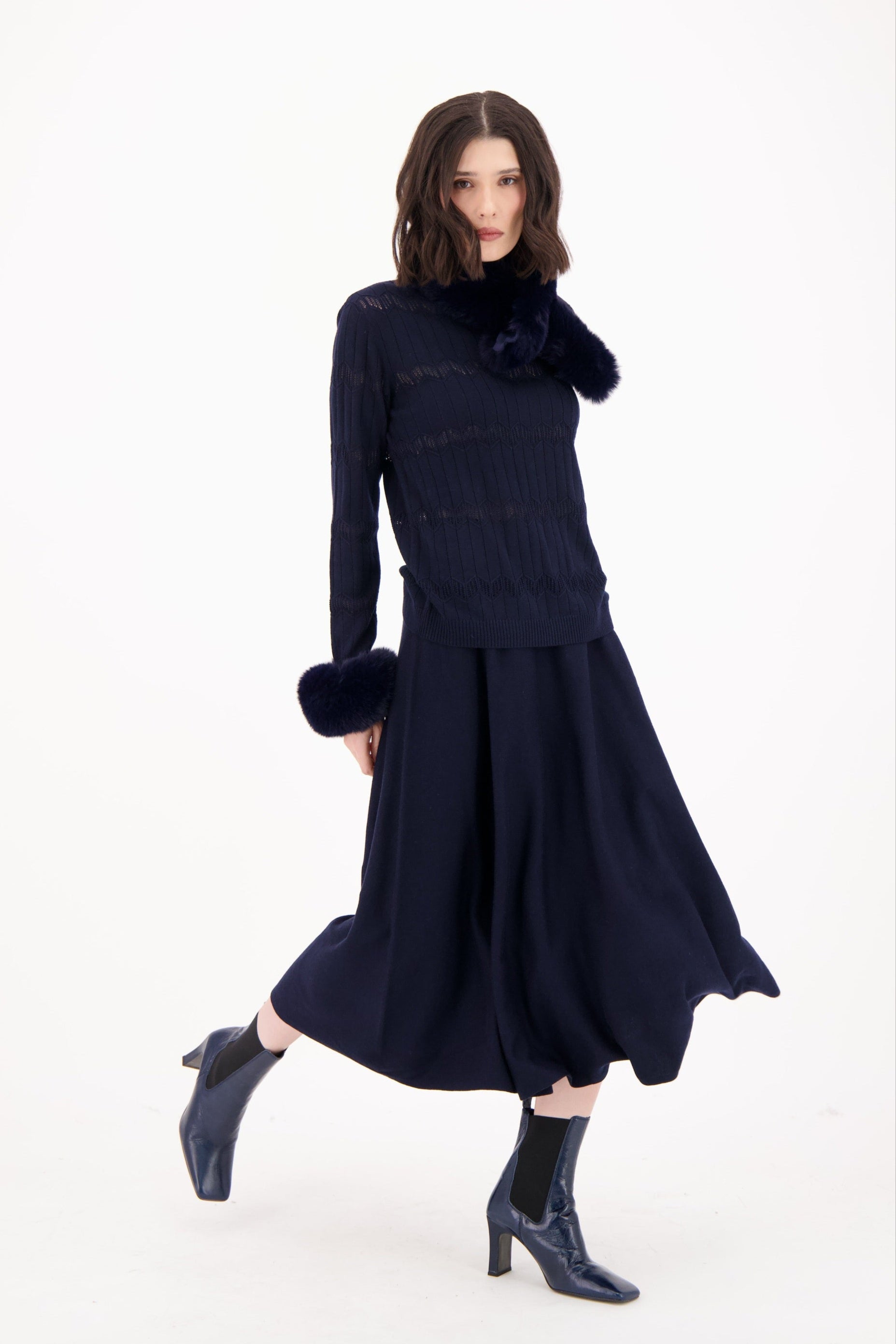 Woman wearing a dark blue dress with matching accessories on a white background