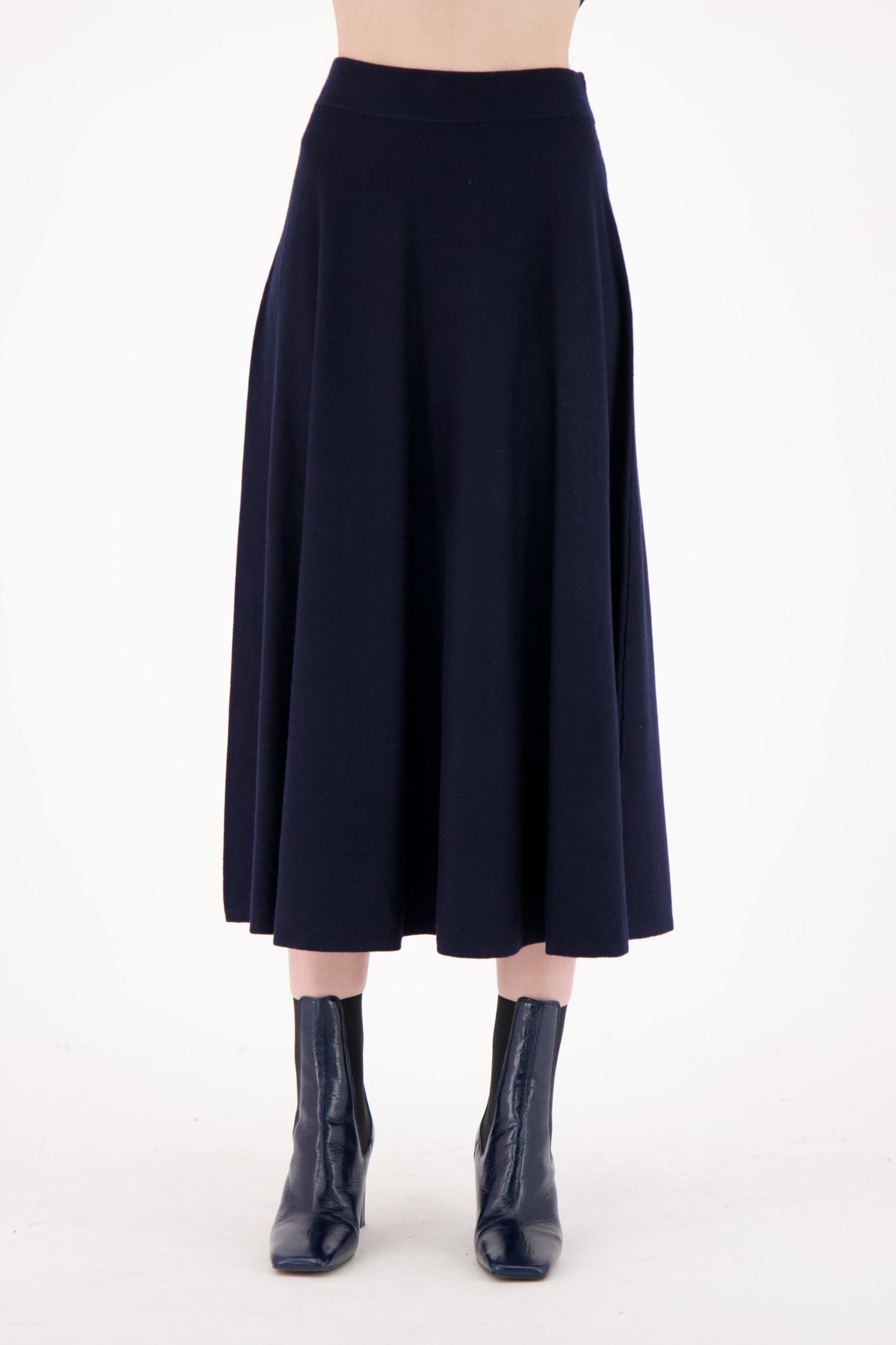 Person wearing a black skirt and black boots on a white background