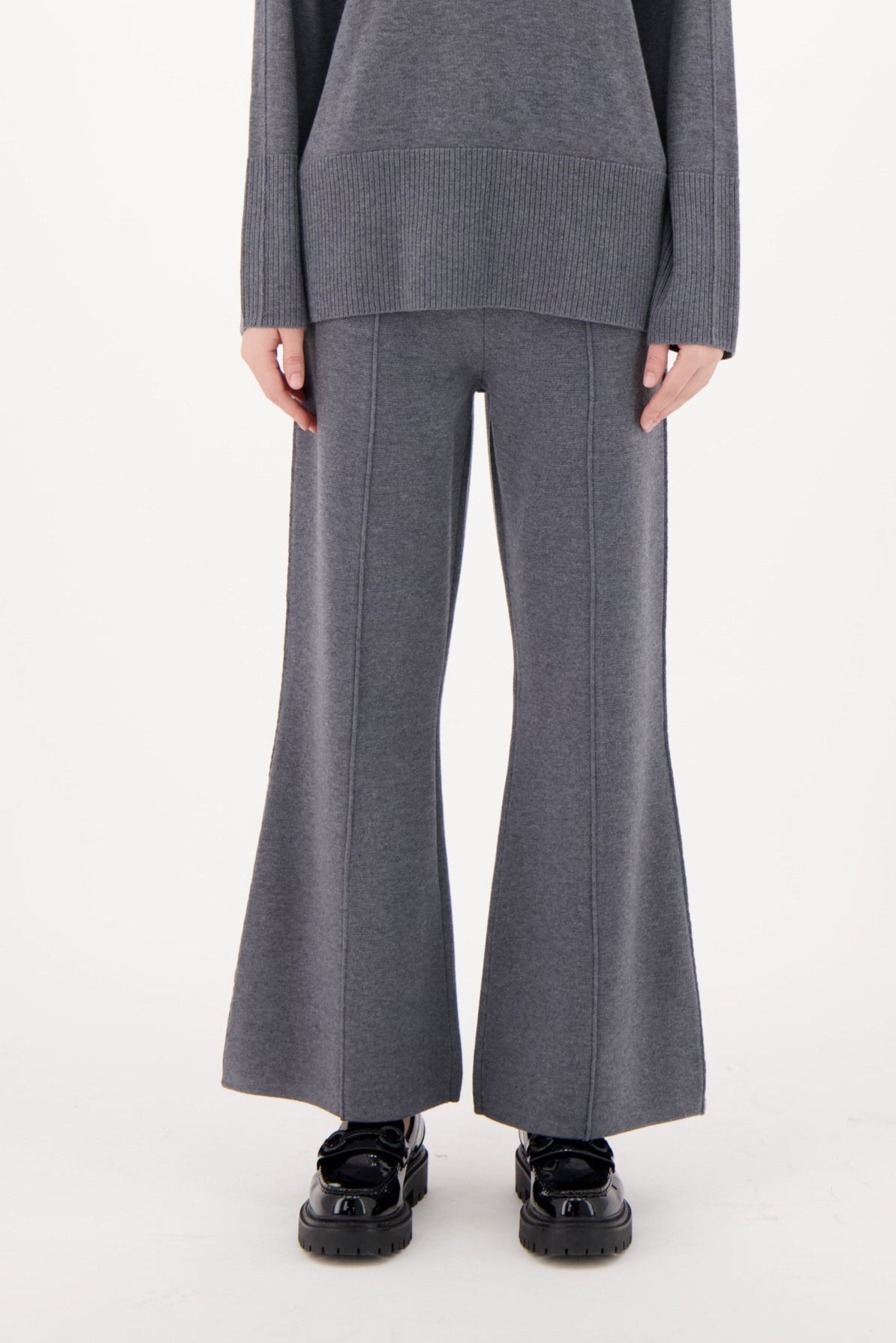 Woman wearing a gray outfit with wide-leg pants on a white background