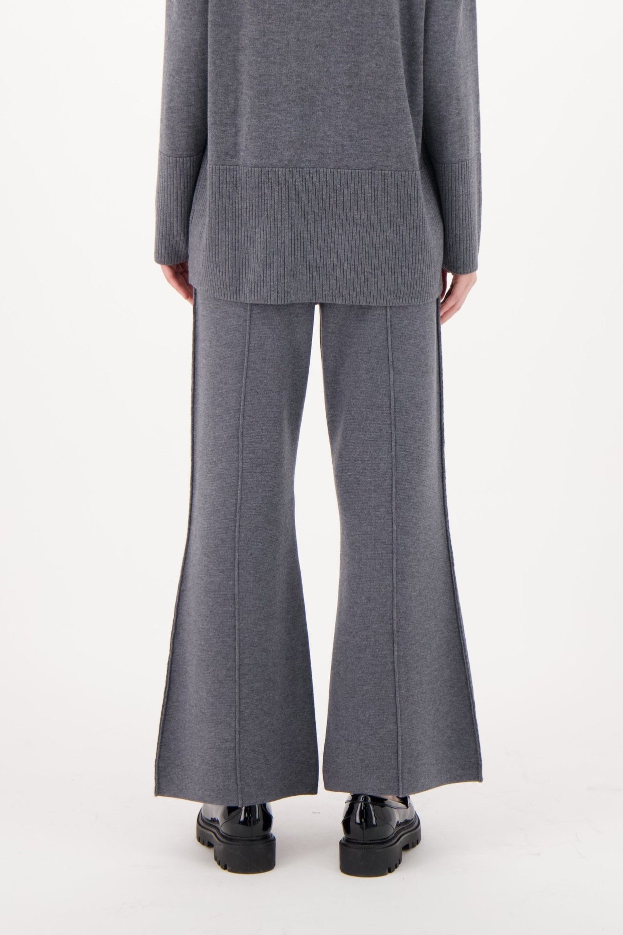 Person wearing a gray suit with wide-leg pants on a white background